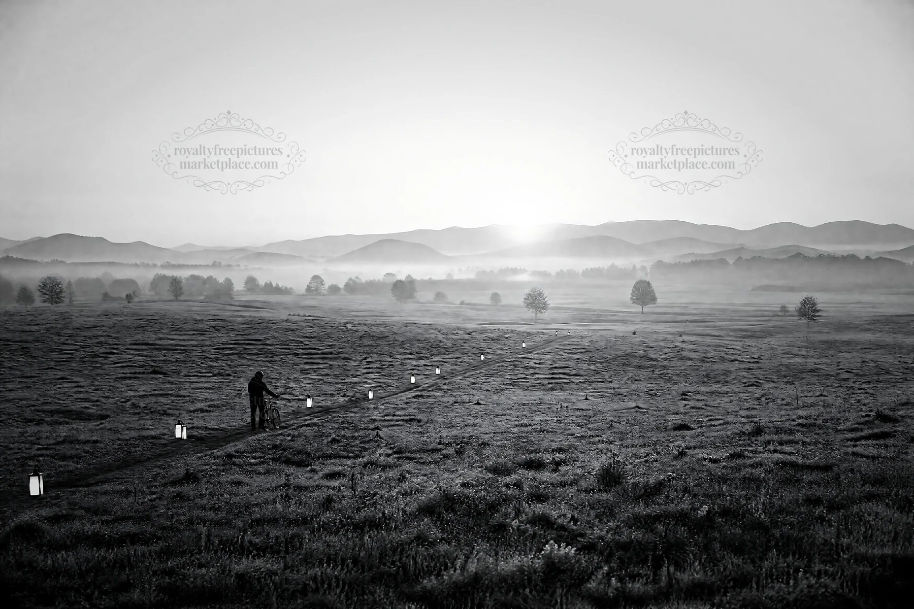 Lantern path in meadow during dawn with distant mountains - AI-generated stock image