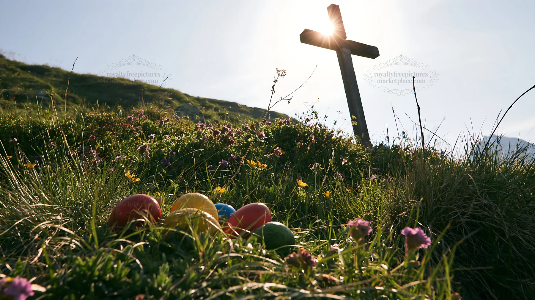 Christian cross in backlit summer meadow with colorful eggs - AI-generated stock image