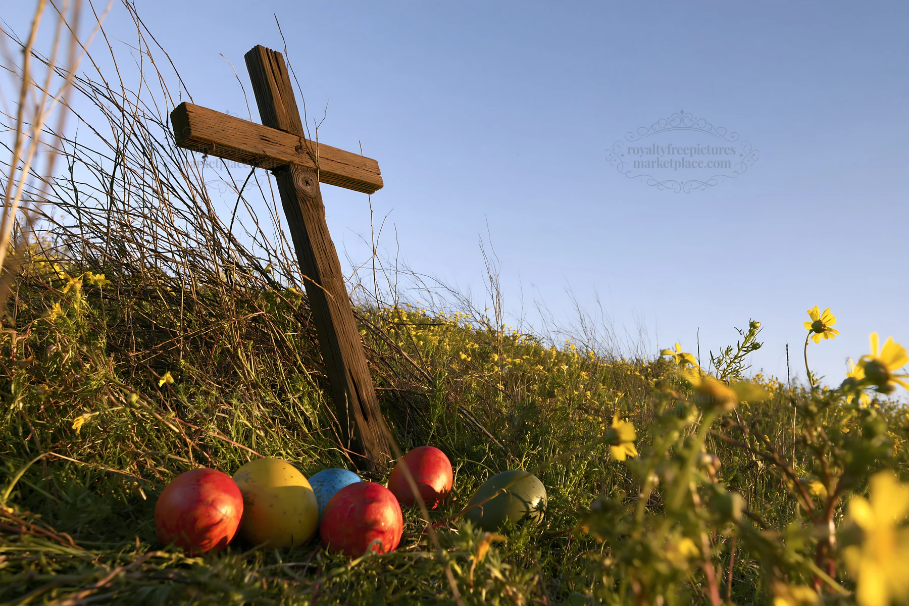 Christian cross among yellow wildflowers and colored eggs - AI-generated stock image