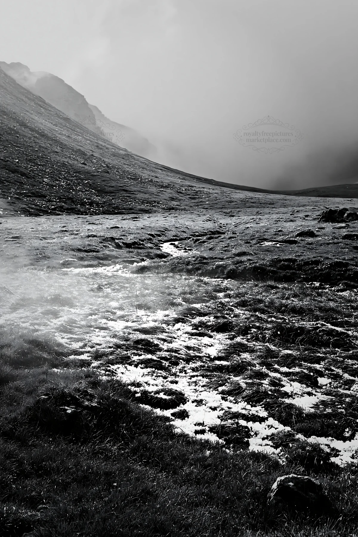 Black and white mountain pass meadow with snow and grass in a cloudy setting - AI-generated stock image