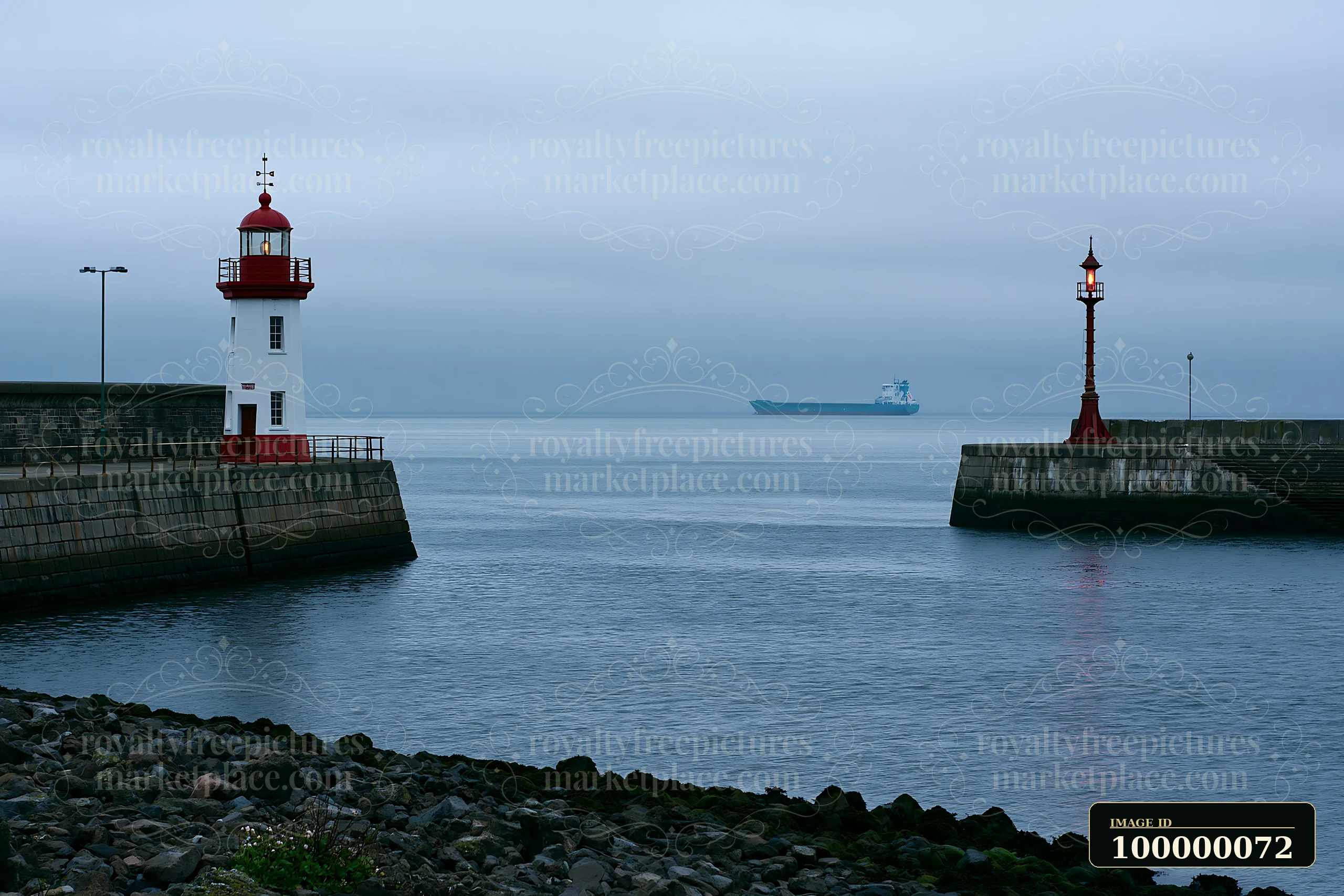 Red and white lighthouse beside a harbor entrance, with a cargo ship visible across calm water.