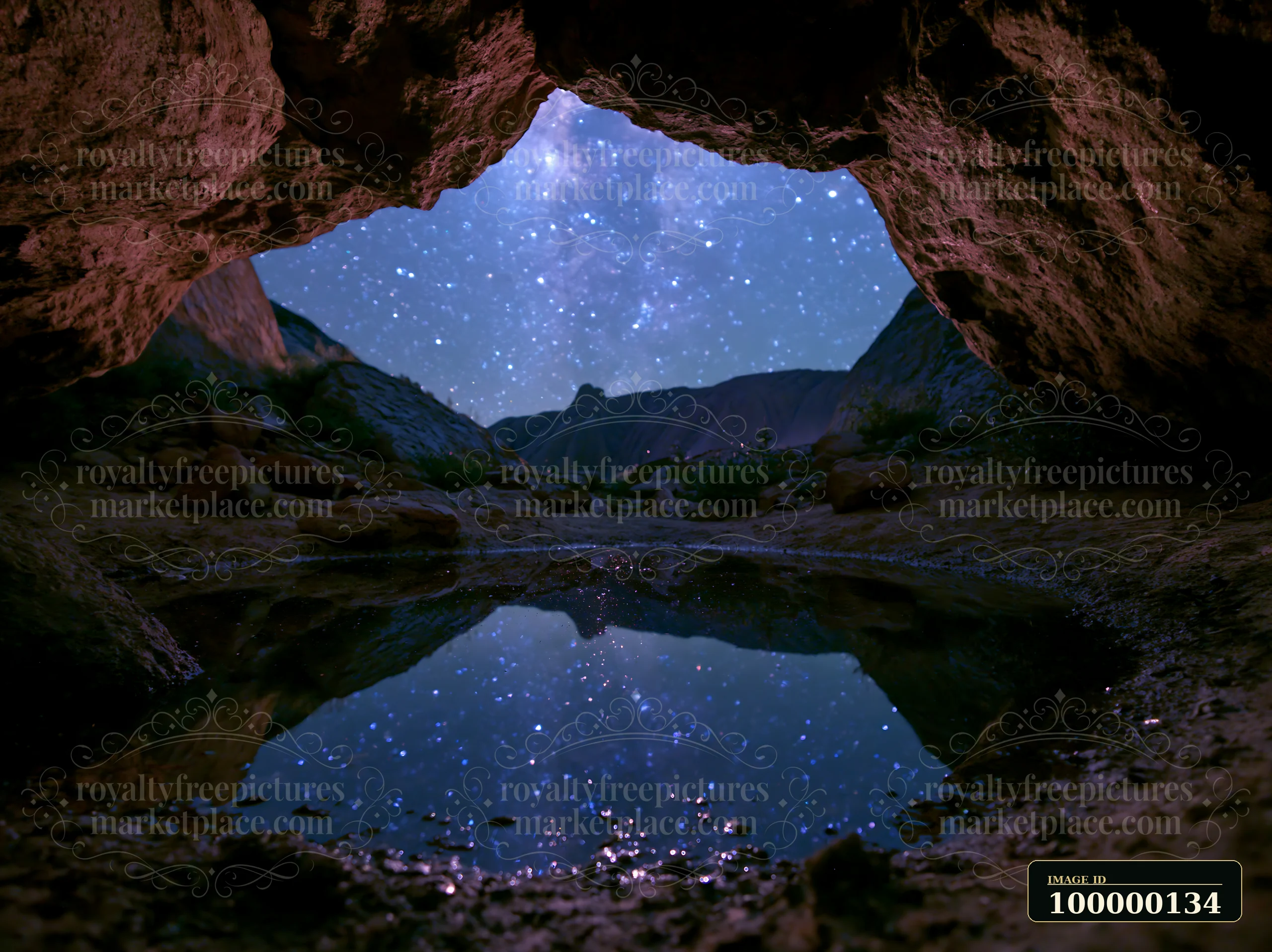 Starry sky and rugged mountains seen through a rocky cave opening, reflected in a small pool.