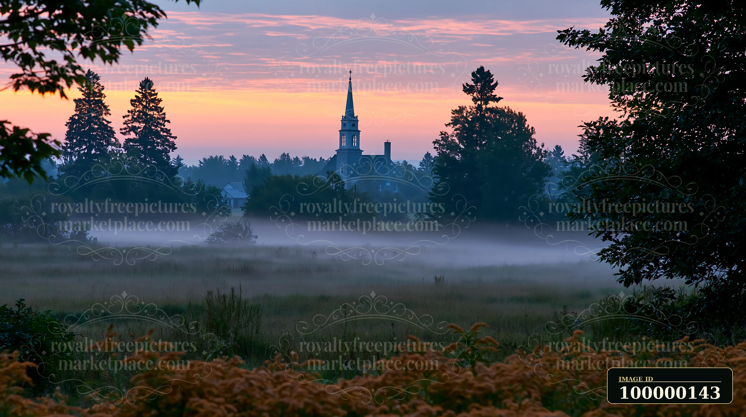 Low fog drifts across a meadow toward a church steeple beneath a pink and orange dawn sky.