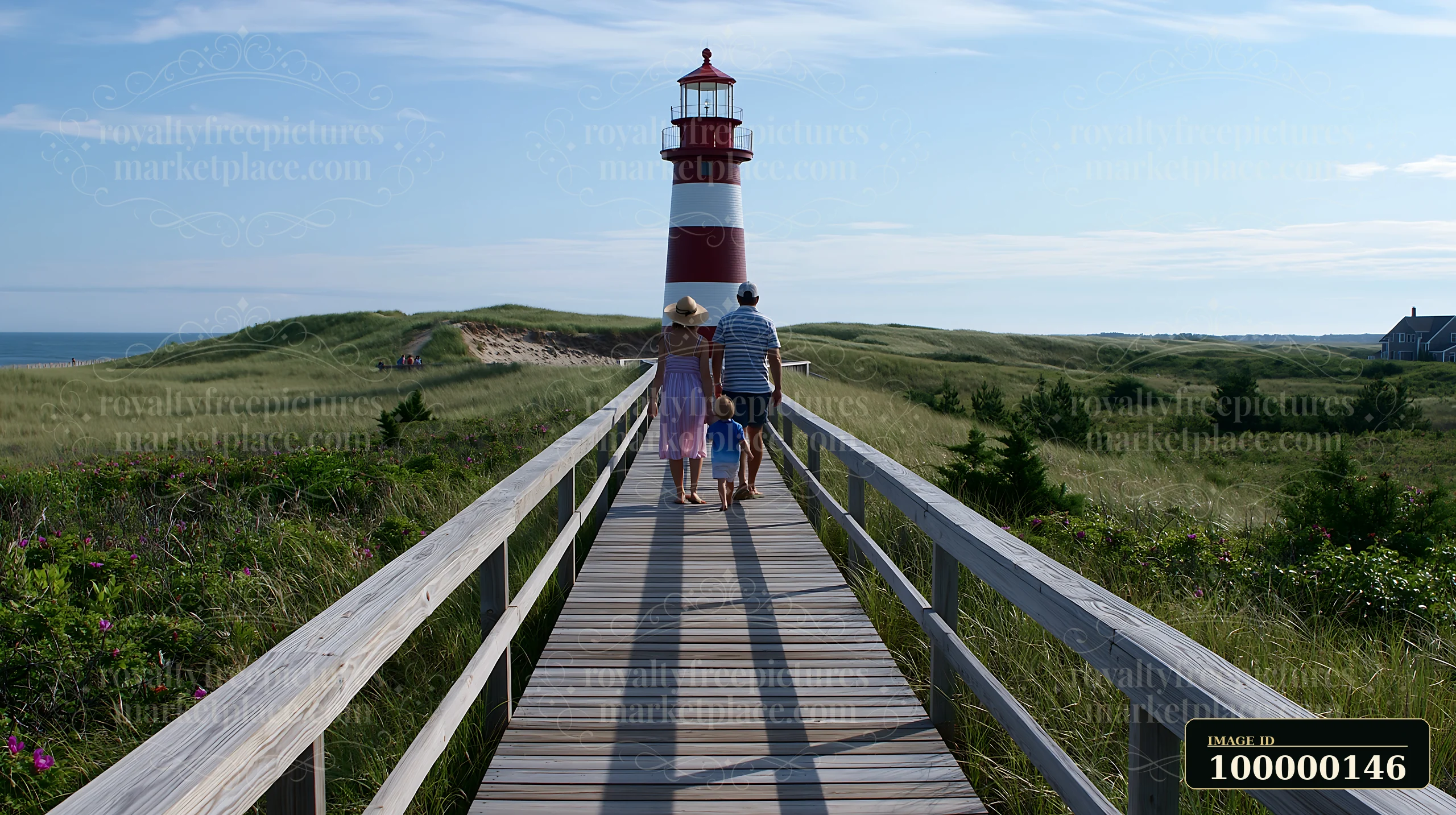Family of three walking on a boardwalk toward a red-and-white lighthouse in coastal dunes