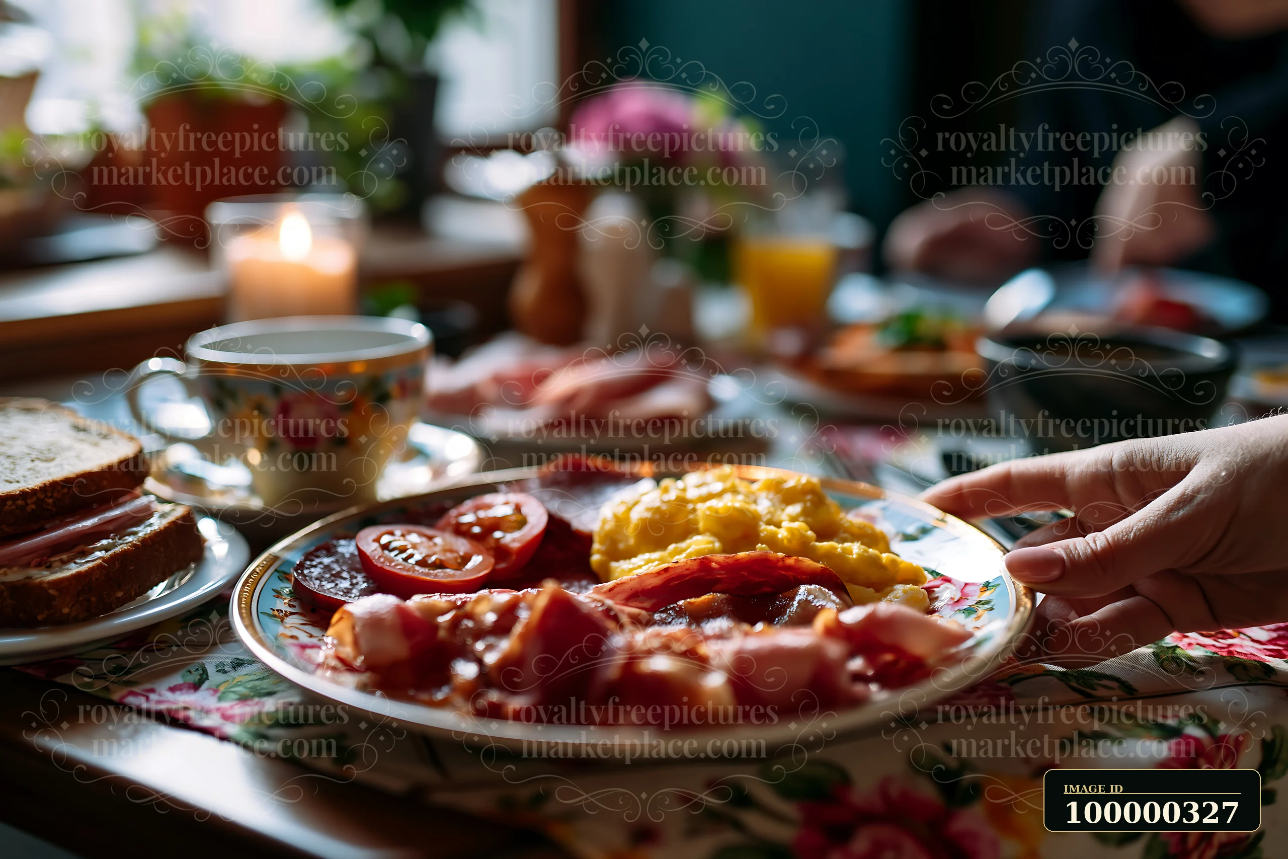 Hand serving a breakfast plate with eggs, bacon, tomatoes, and toast at a warmly lit dining table.