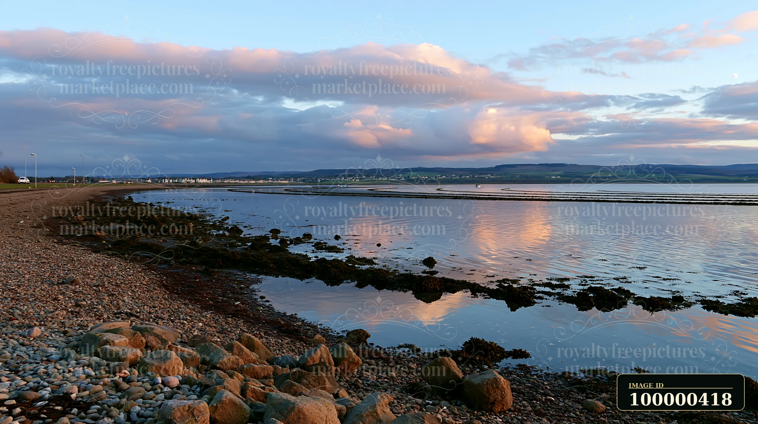 The coastline with mussel farms shows low tide, exposing rocky areas and seaweed along the shore.