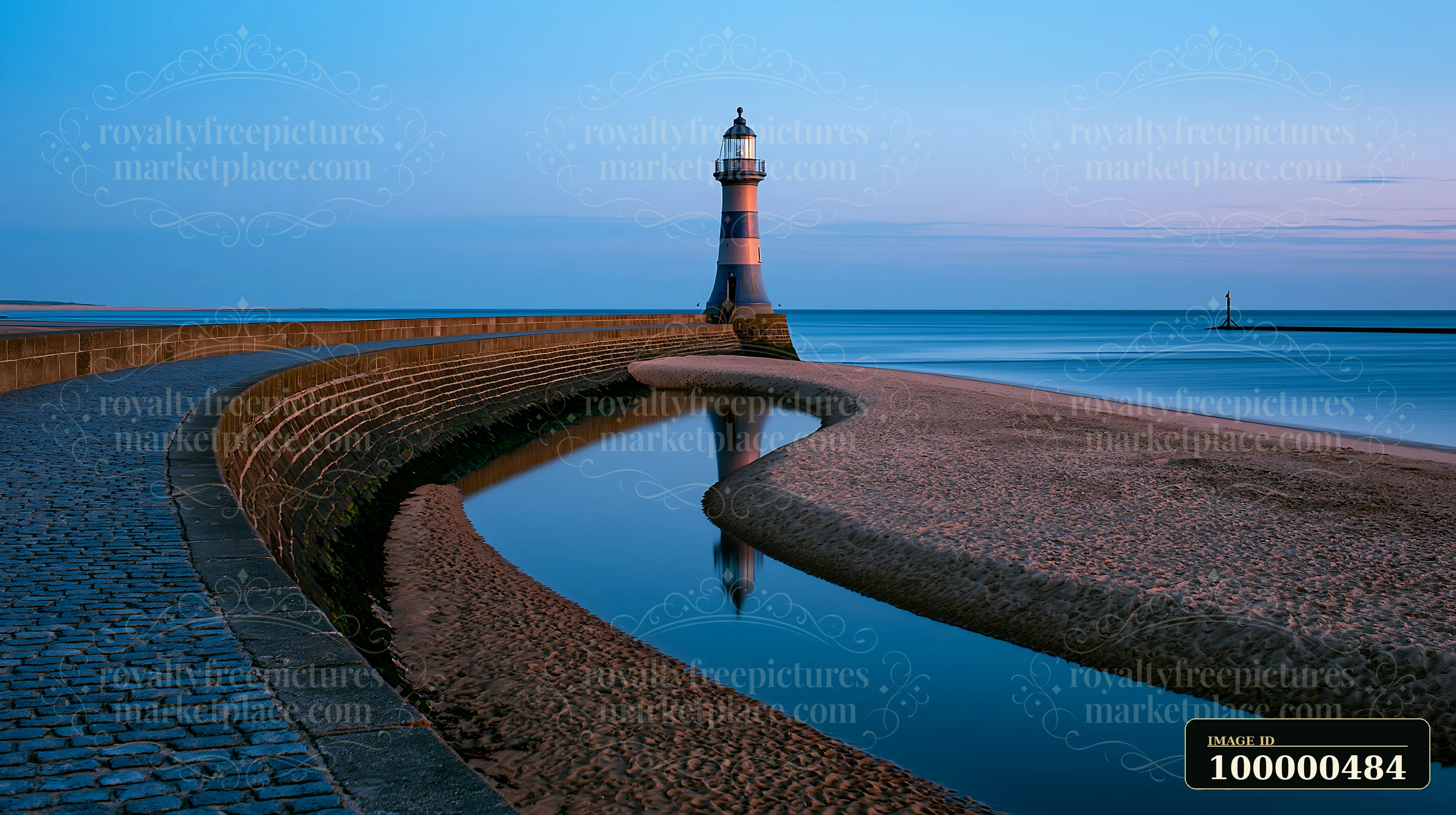 A lighthouse stands beside a winding river as it meets the sea at dusk.