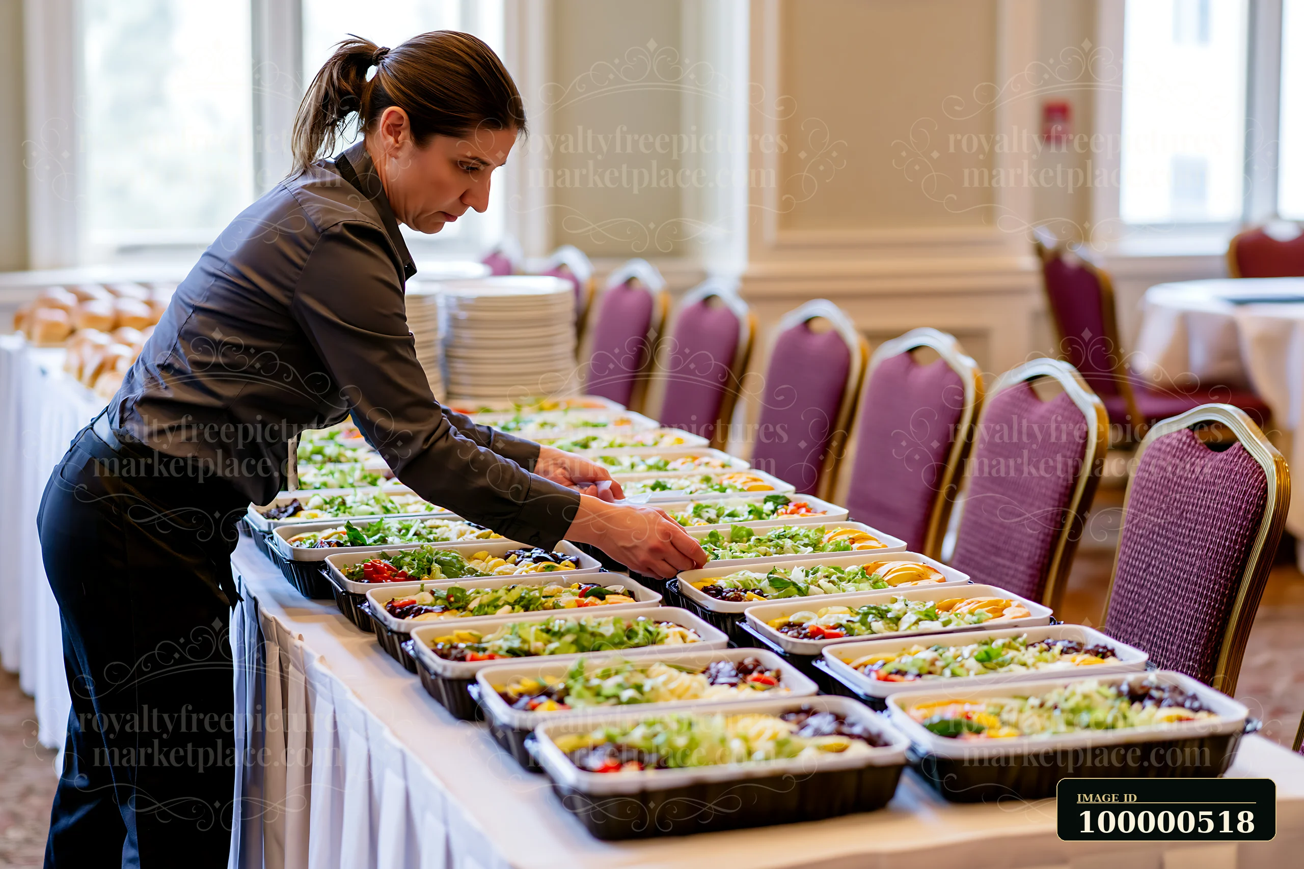 A server is setting up a catering buffet in a banquet hall.