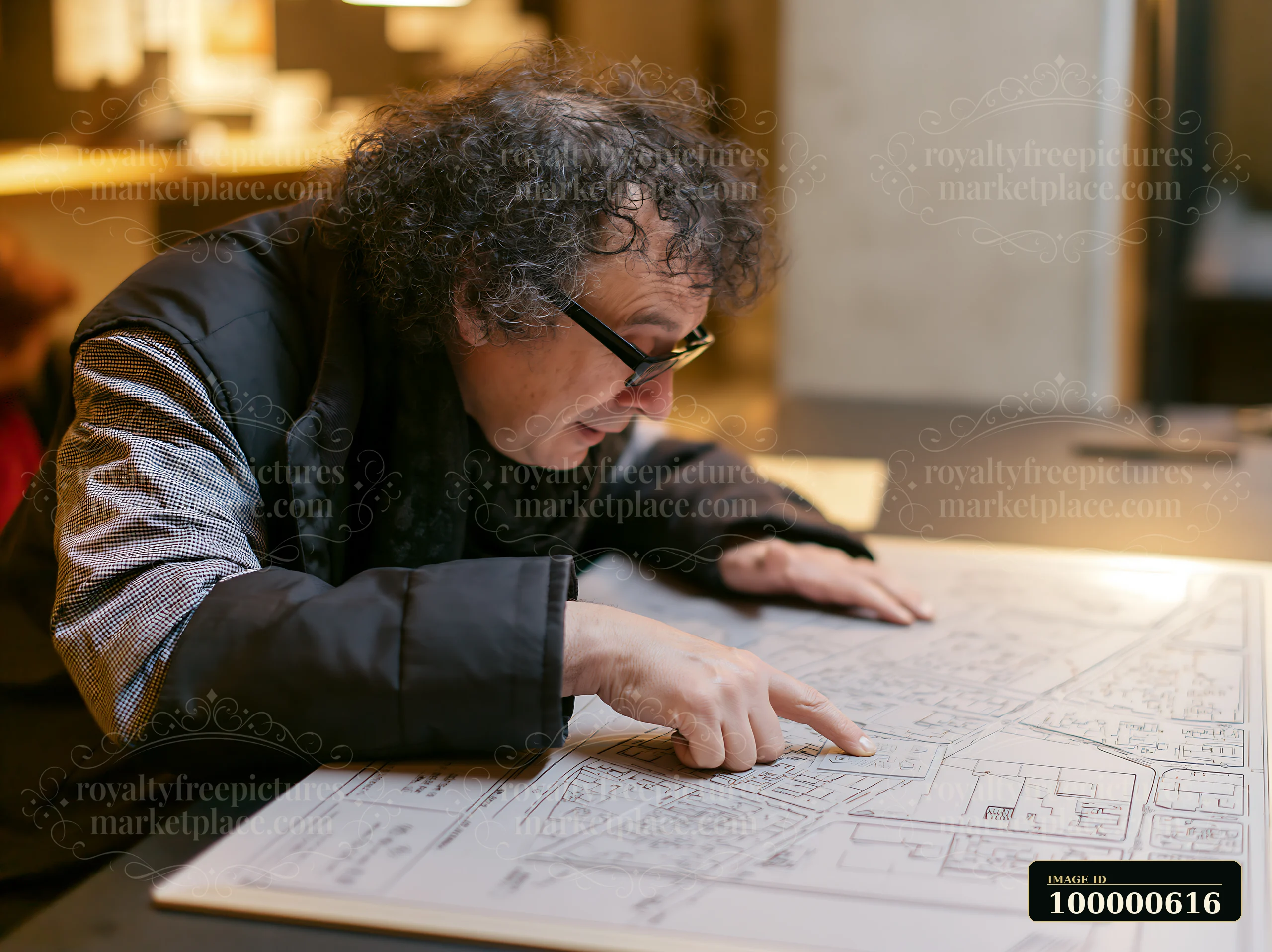A man studies a map while pointing at specific areas in an office space.