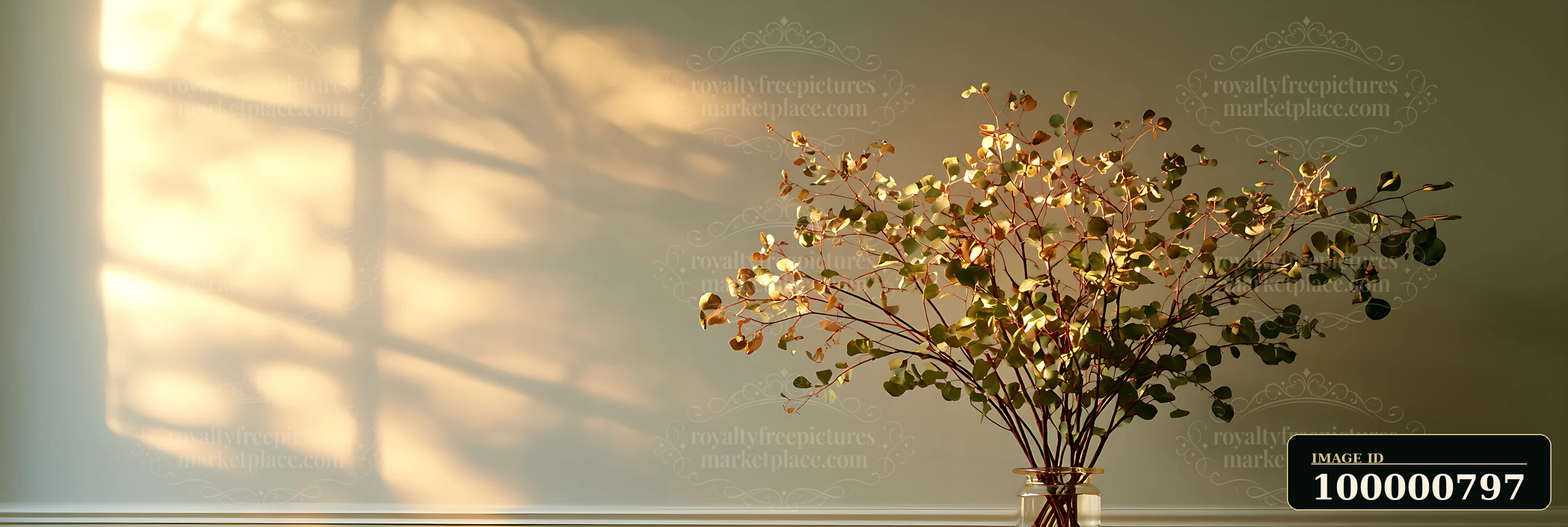 Dried branches filled with leaves are arranged in a clear glass vase placed on a wooden table.