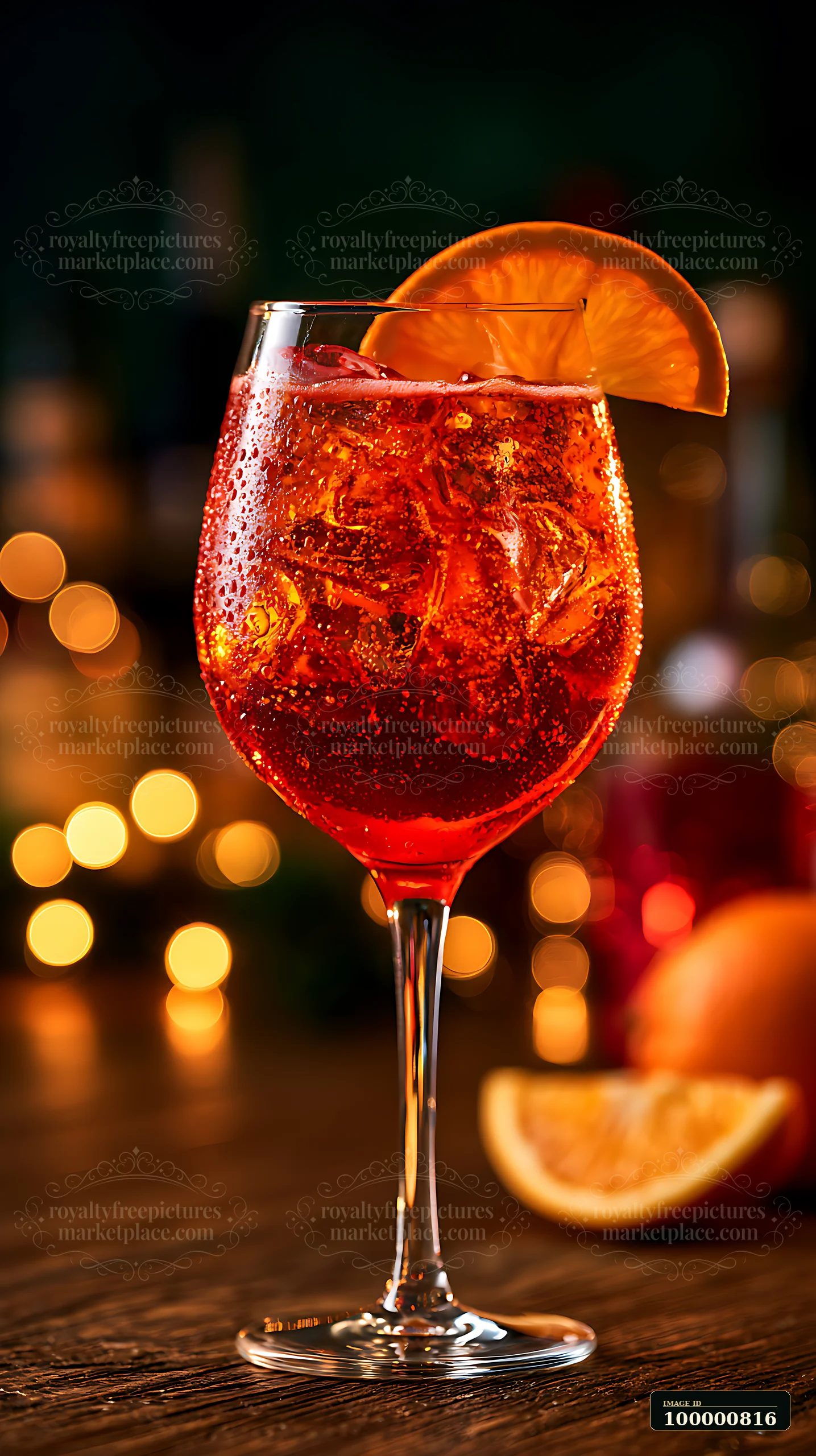 A red cocktail with ice sits on a wooden table.