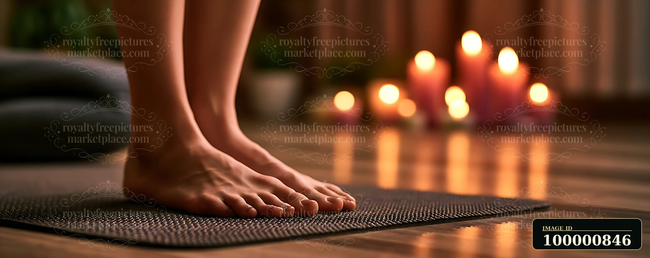 A person stands on a yoga mat in a room with soft lighting and lit candles nearby.