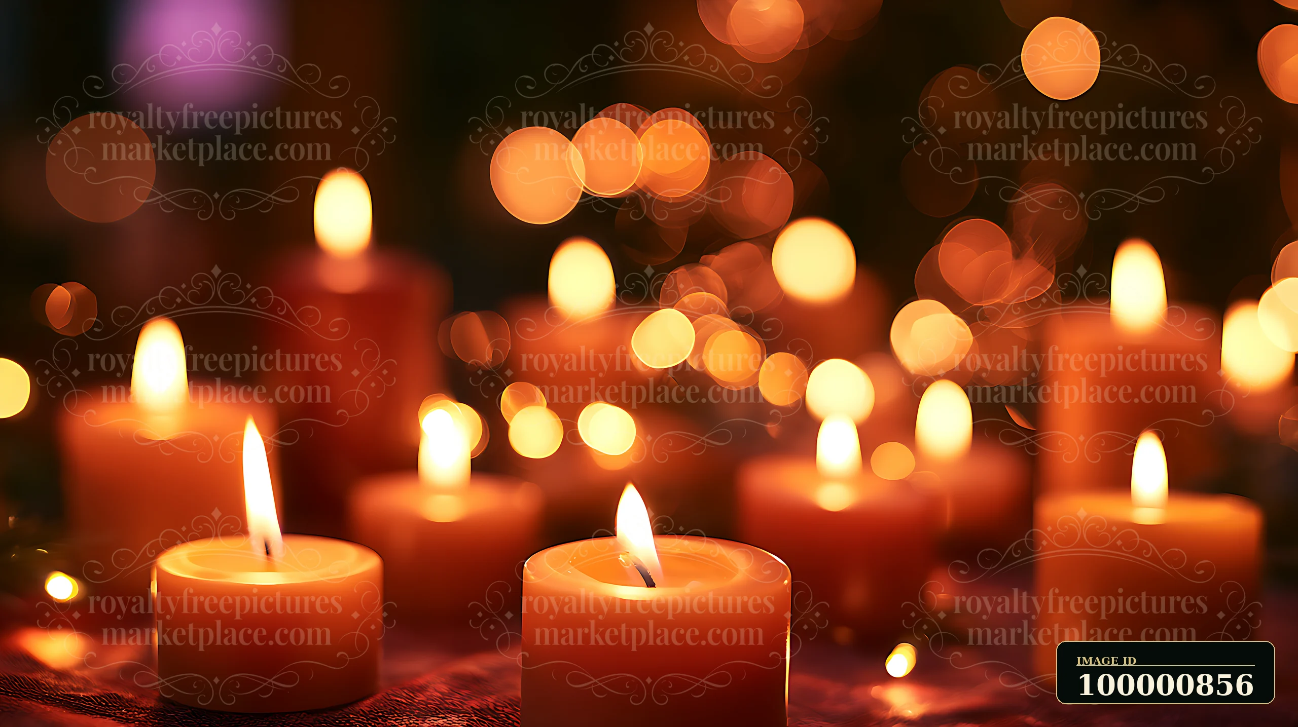 Candles of various sizes burn softly in a dark environment, creating a warm ambiance.