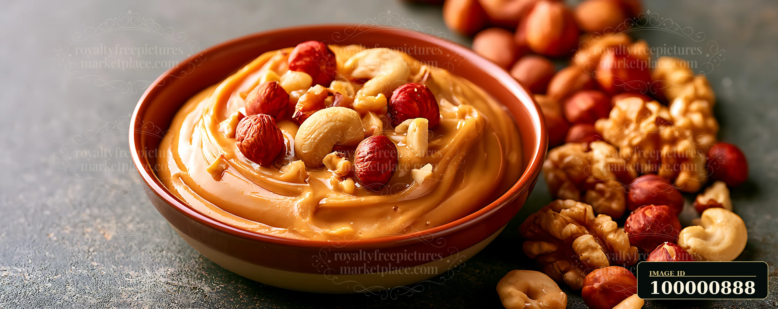 A bowl filled with creamy nut butter sits on a dark surface surrounded by various mixed nuts.