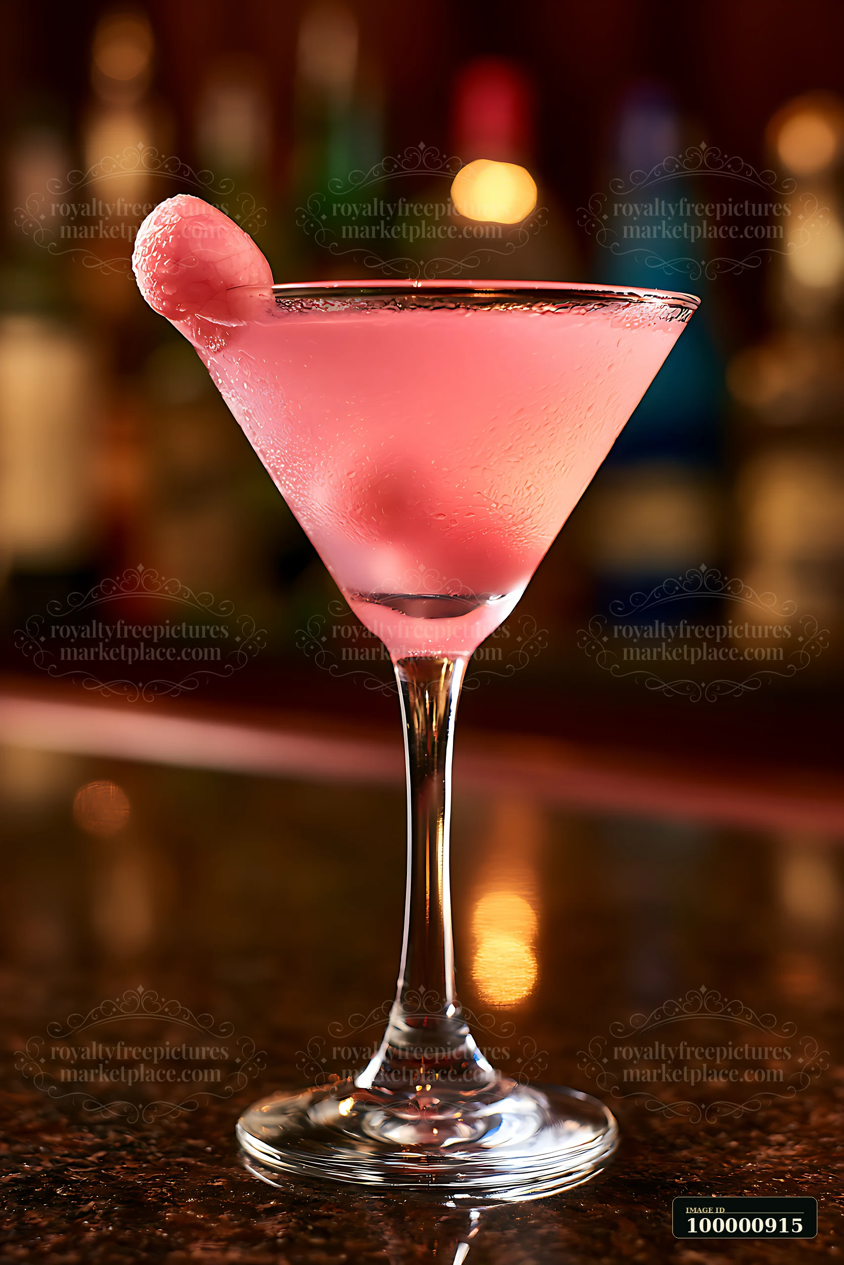 A pink cocktail with a fruit garnish sits on a dark wooden bar.