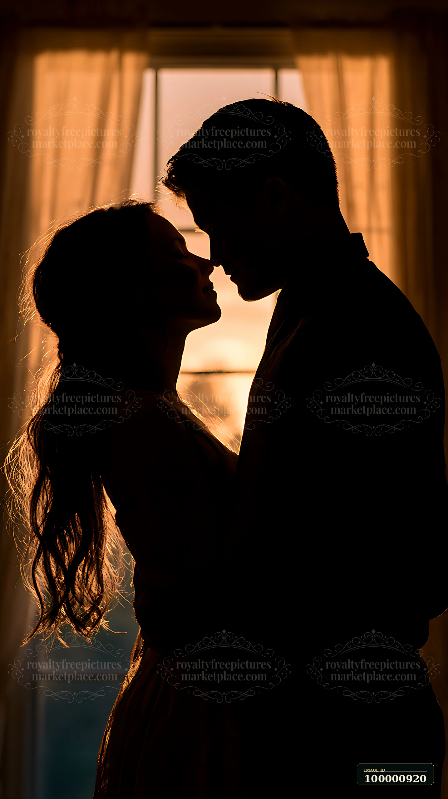 A couple stands closely together in silhouette as the sun sets behind them.