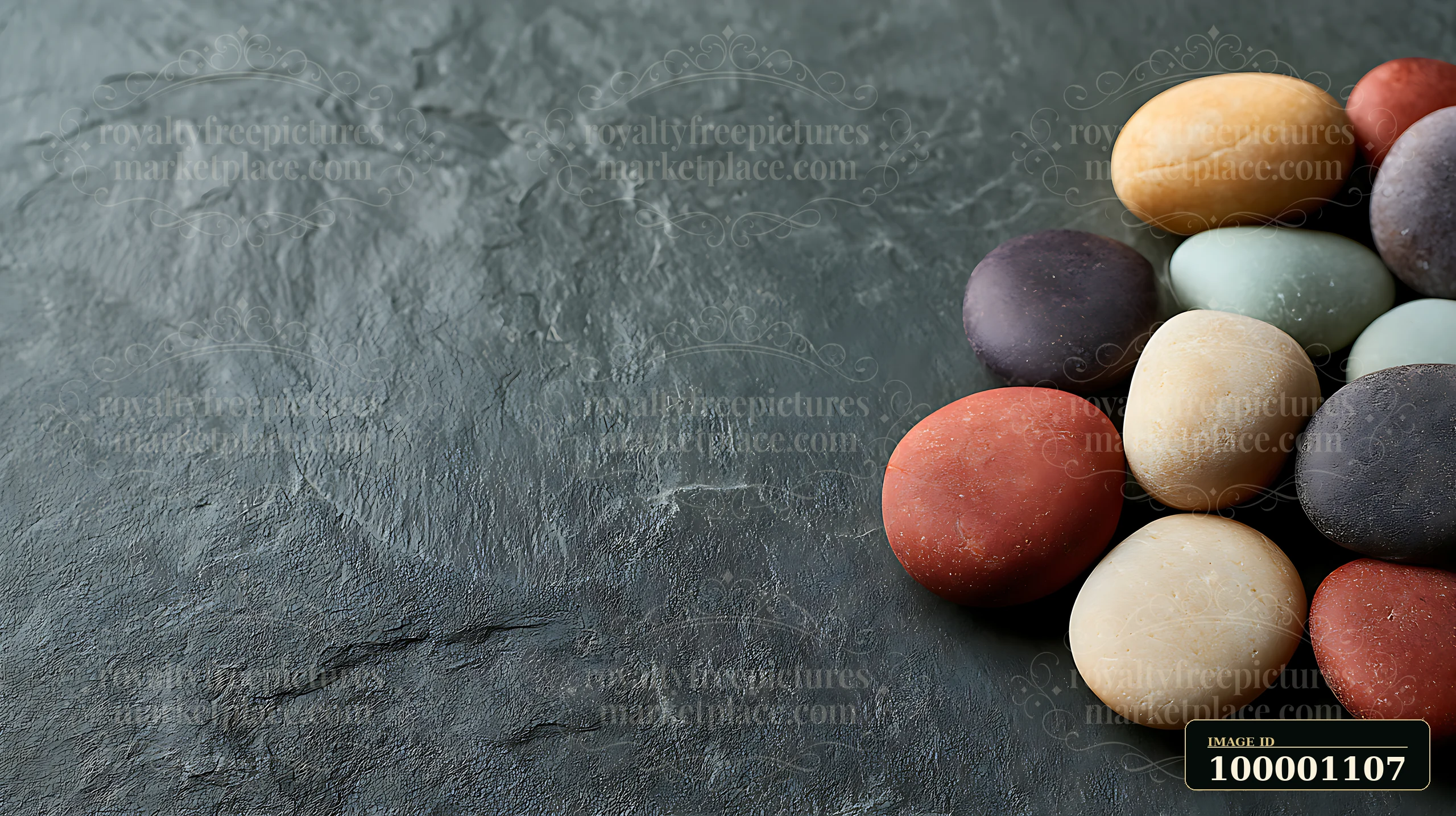A collection of various colored stones is placed on a dark slate surface.