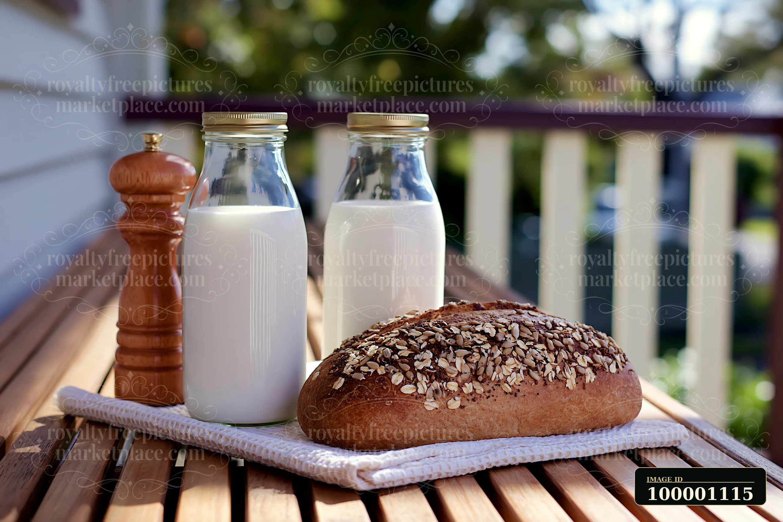 Two glass milk bottles arranged beside fresh bread on a wooden table outdoors.