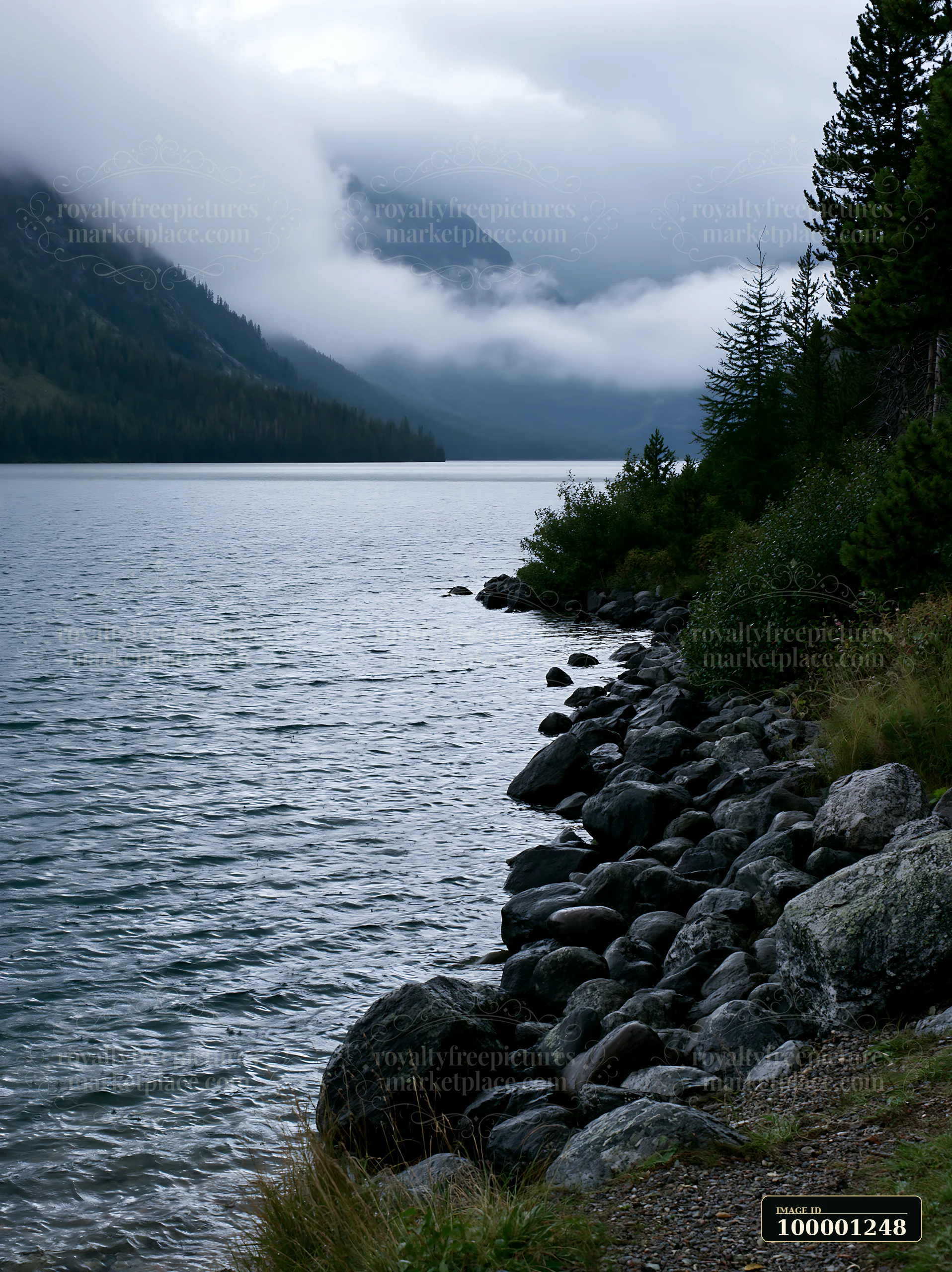 A clear alpine lake beneath cloud-covered peaks reflects the surrounding landscape.