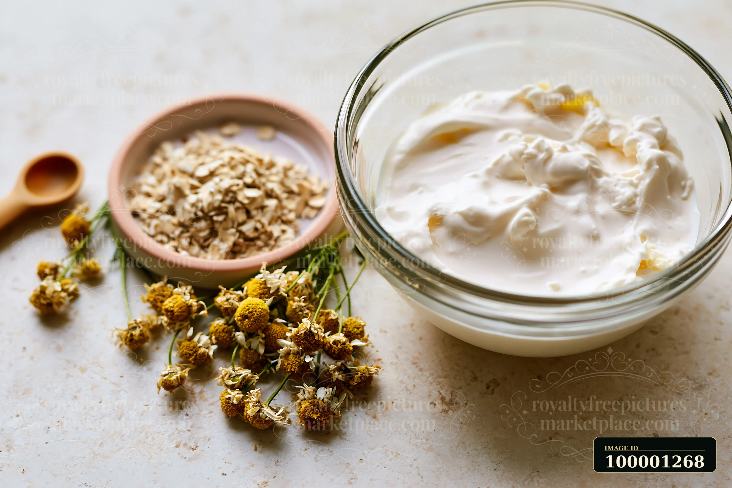 A bowl contains a creamy mixture made with natural ingredients, including oats and dried flowers, arranged on a kitchen surface.