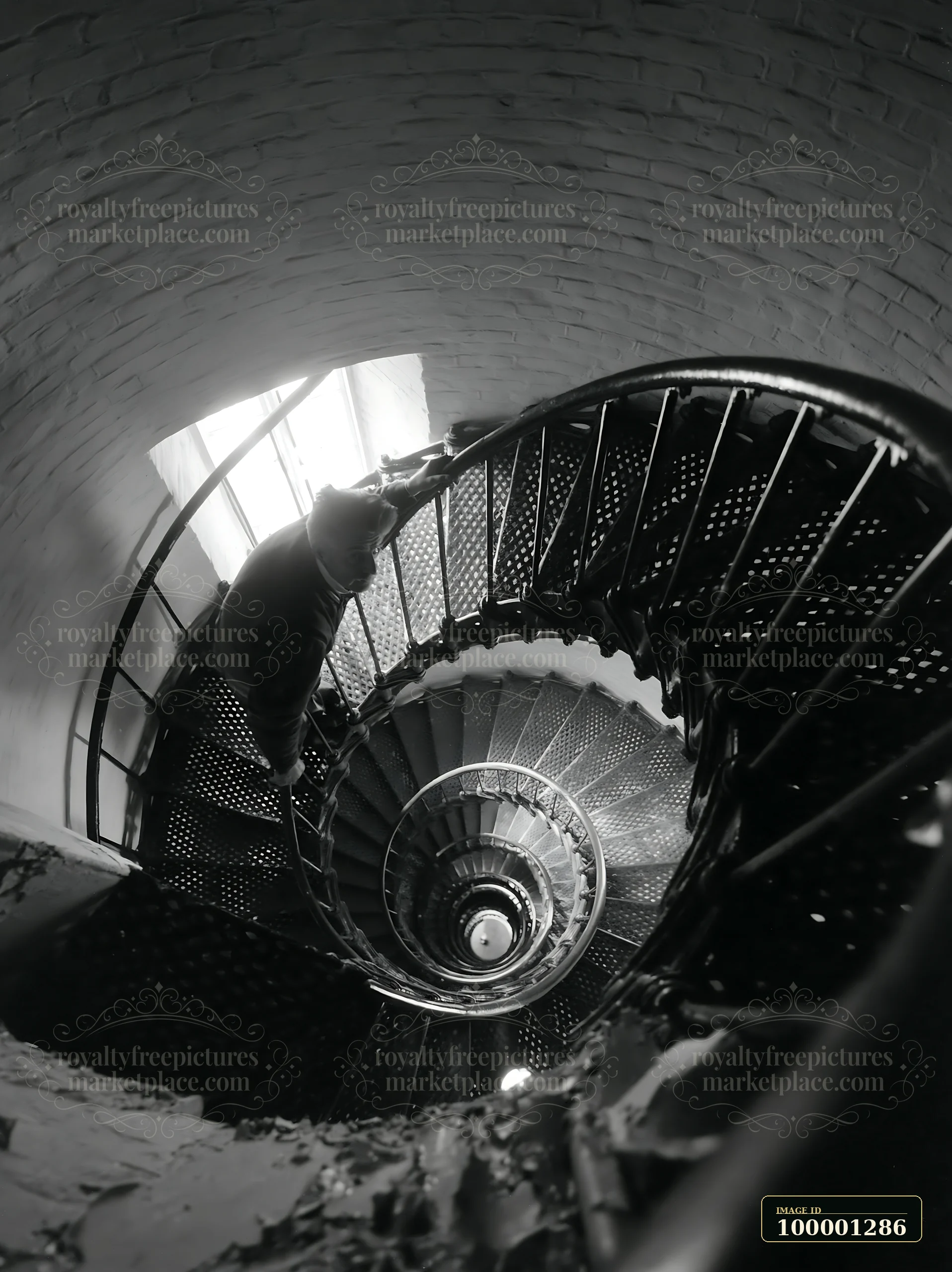 A lighthouse maintenance worker climbs a spiral staircase inside the lighthouse, focusing on the task.