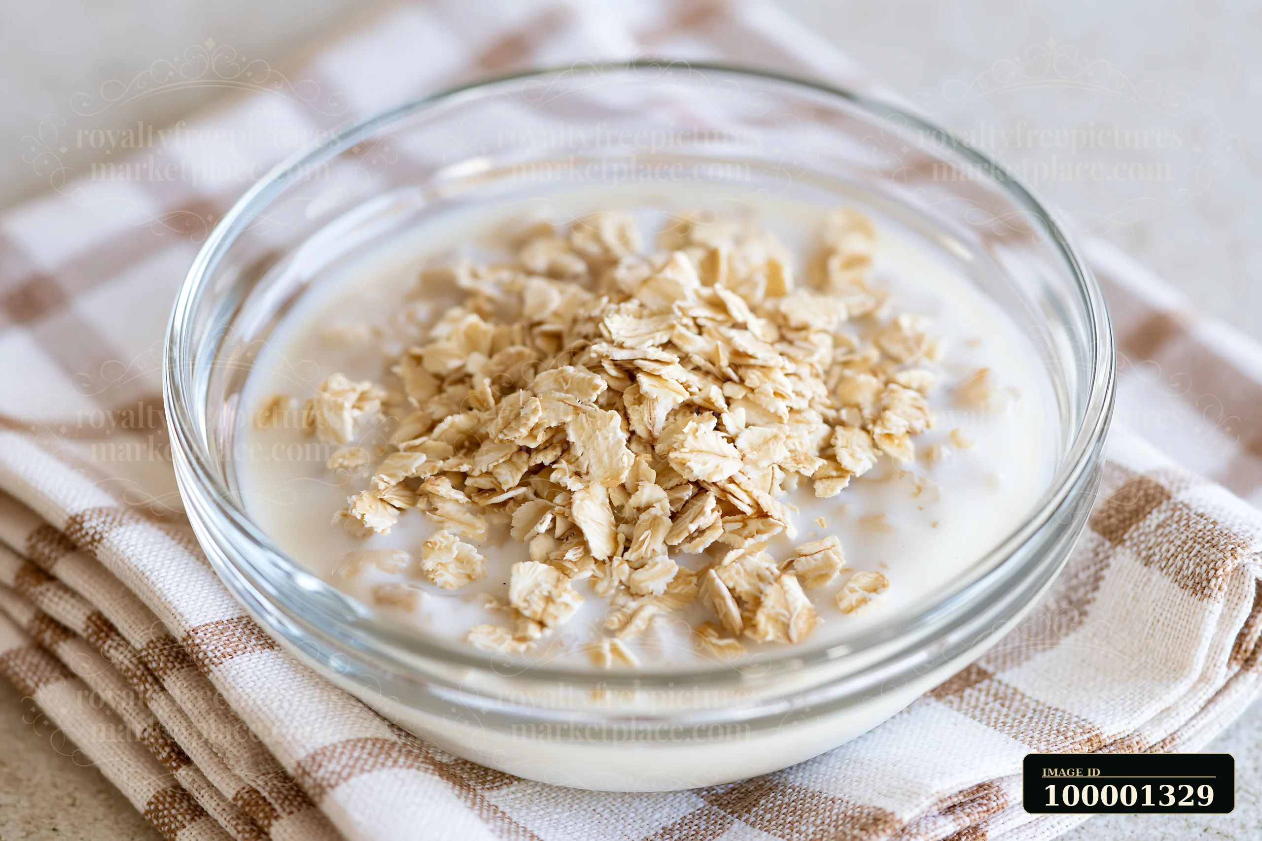 A bowl holds a cream dose topped with oat flakes on a light checkered cloth.