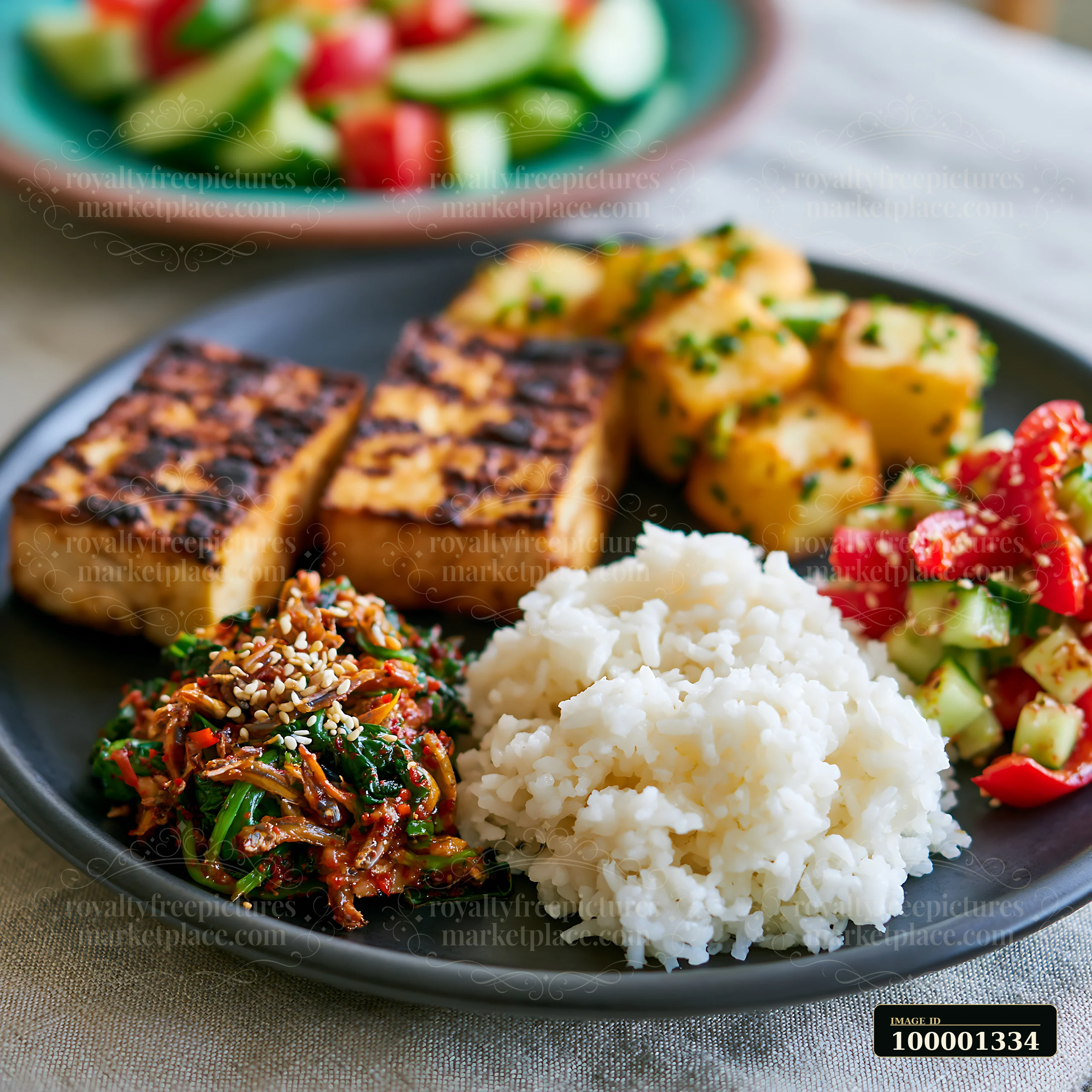A breakfast plate with Korean breakfast features grilled tofu, rice, and colorful vegetables.