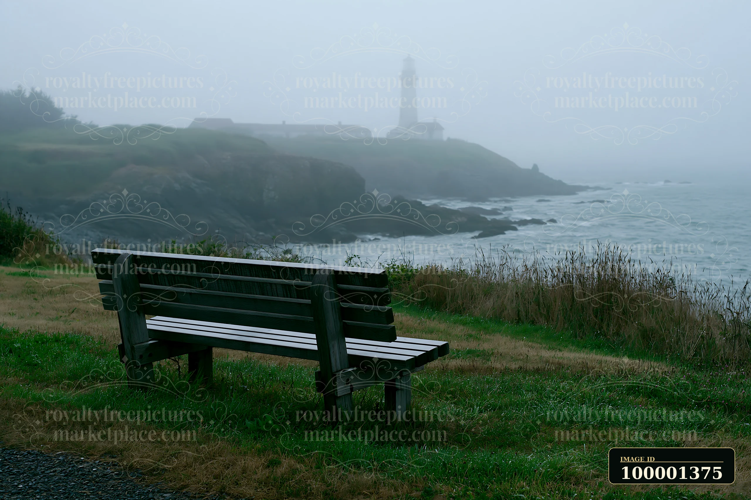 A lighthouse in heavy ocean fog stands on a rocky shore with a bench in the foreground.