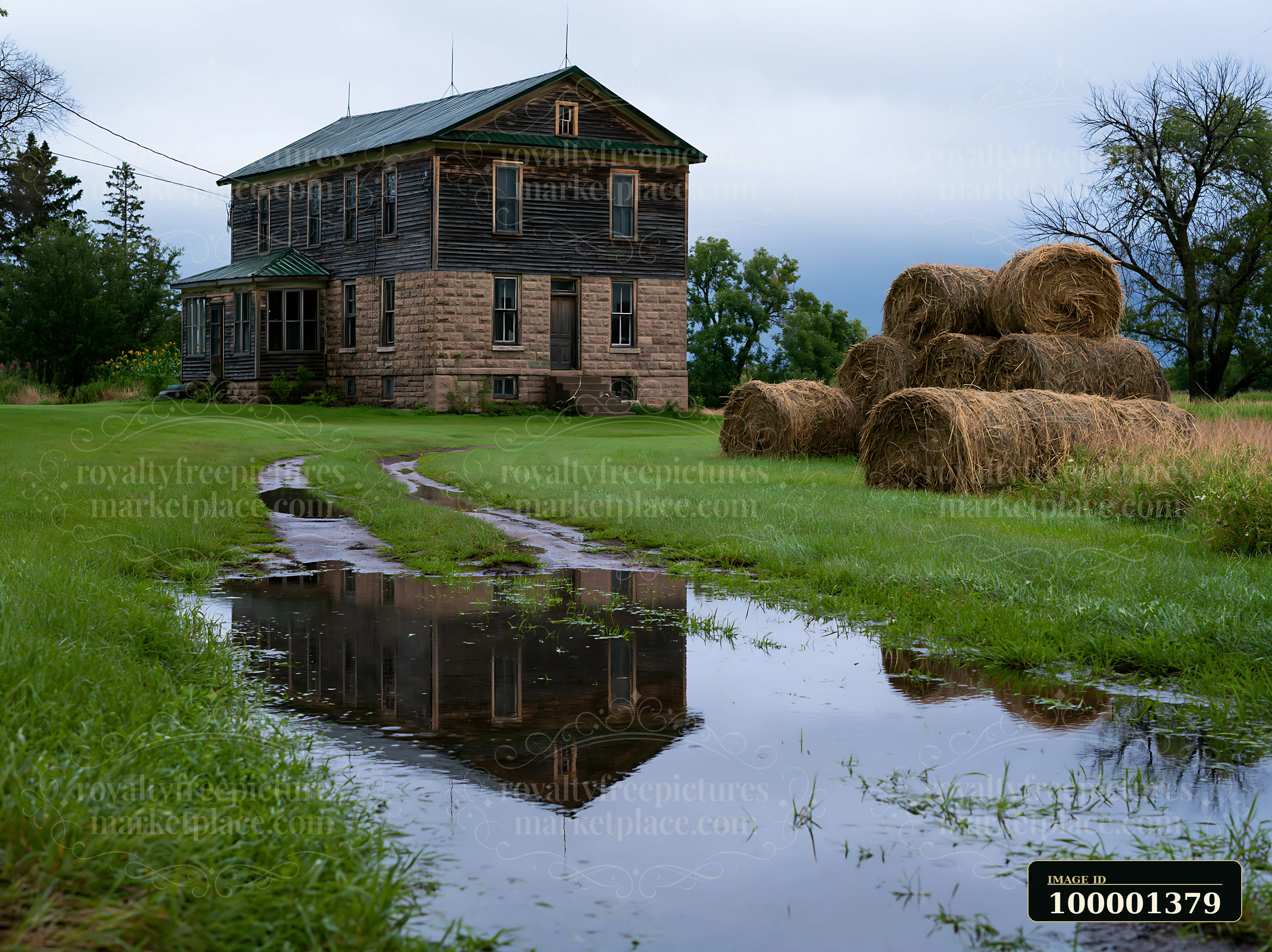 A farmhouse with hay bales sits on a grassy area.