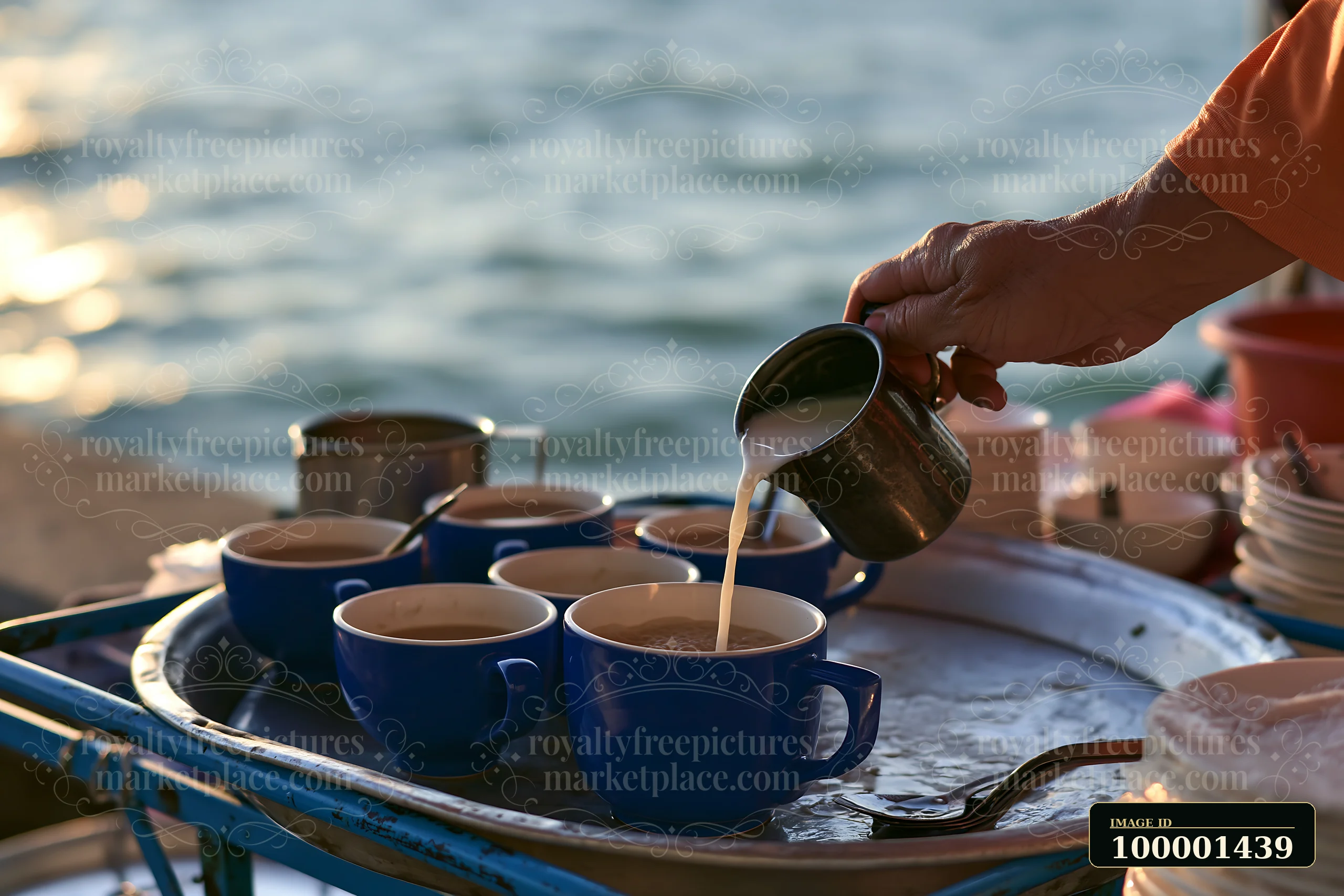 A street food vendor adds milk to a cup of tea at a market near the waterfront.