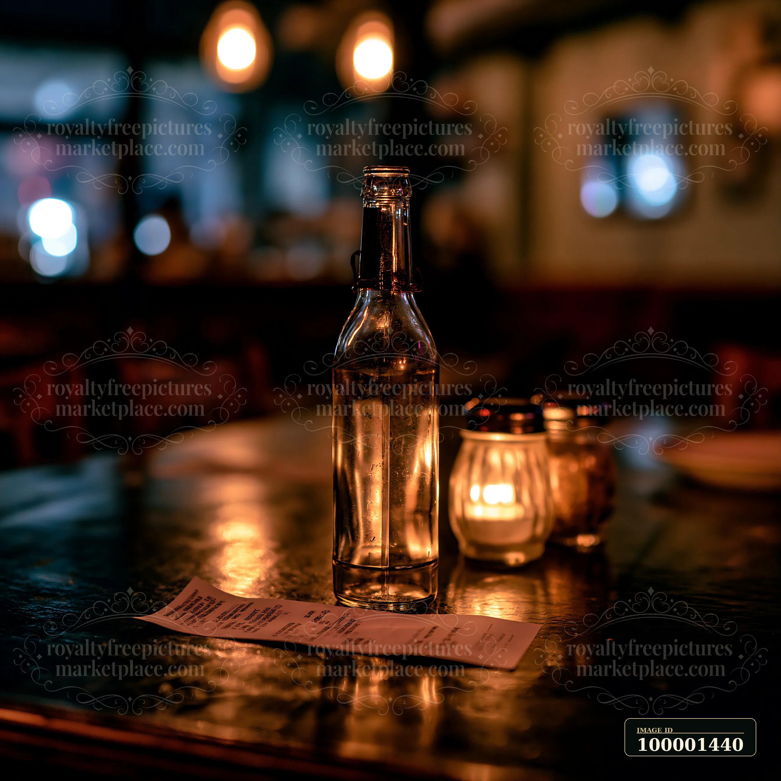 A clear, empty bottle rests beside a receipt on a wooden table in a dimly lit restaurant.