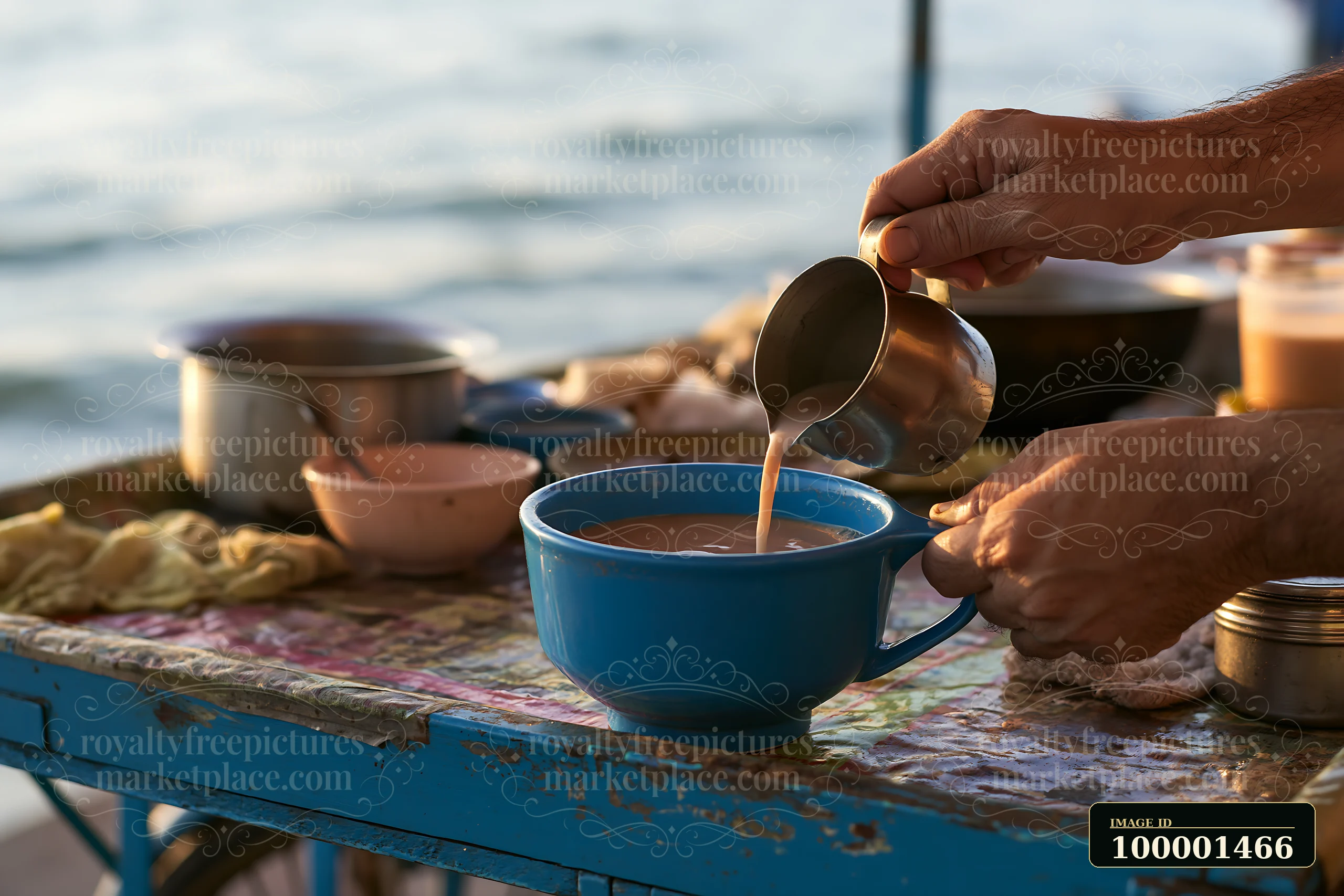 A street food vendor adding milk to tea at a busy food stall by the water.