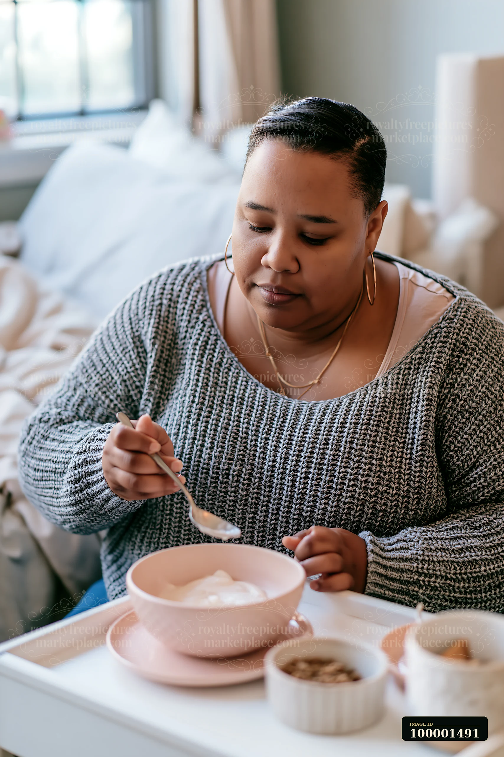 A person with limited hand mobility using utensils sits at a table eating breakfast in a cozy home setting.