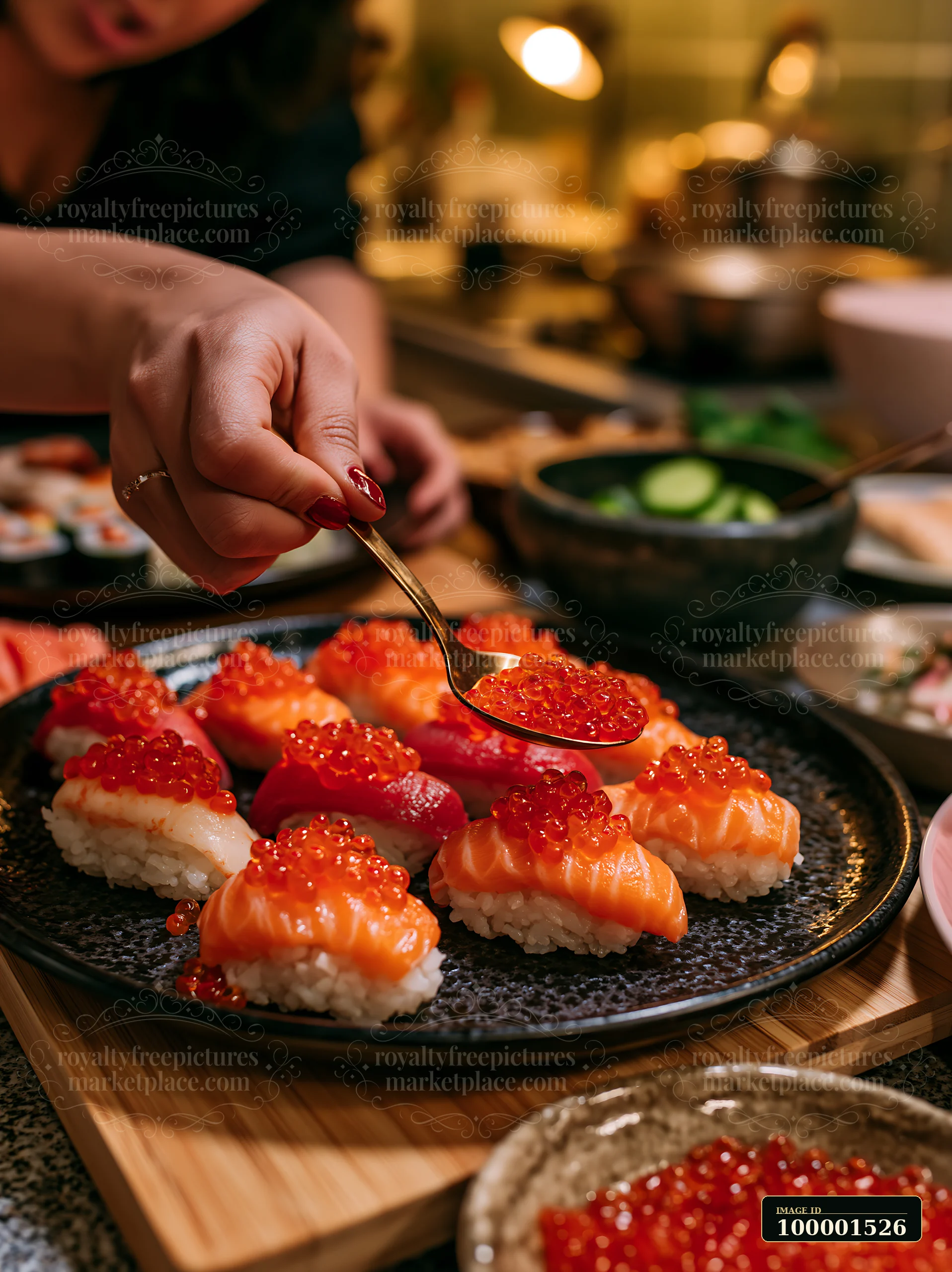 A person uses a spoon to place roe on top of nigiri in a warm kitchen.
