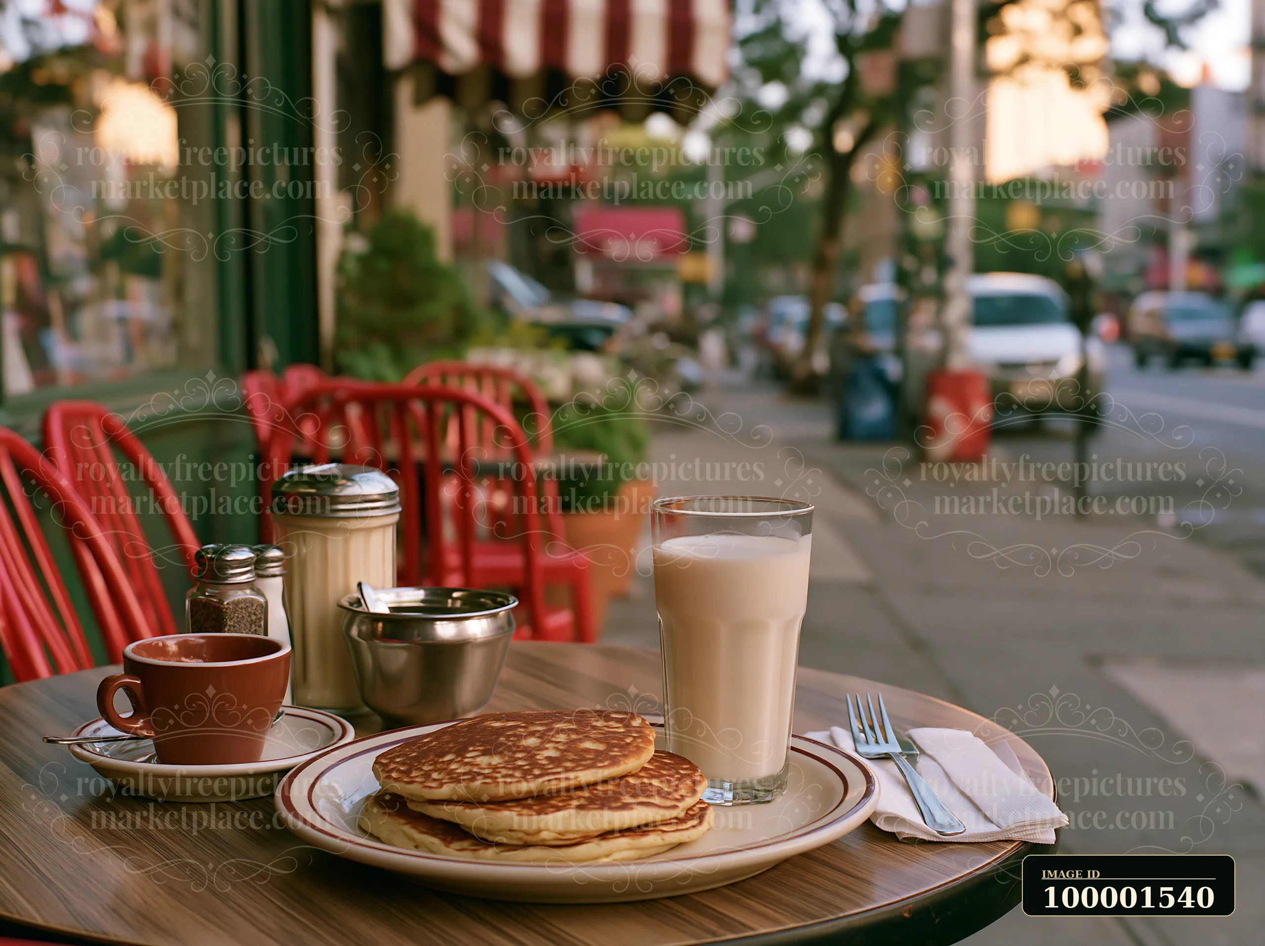 A table outside a cafe shows a plate of pancakes alongside a glass of milk and a small cup of coffee.