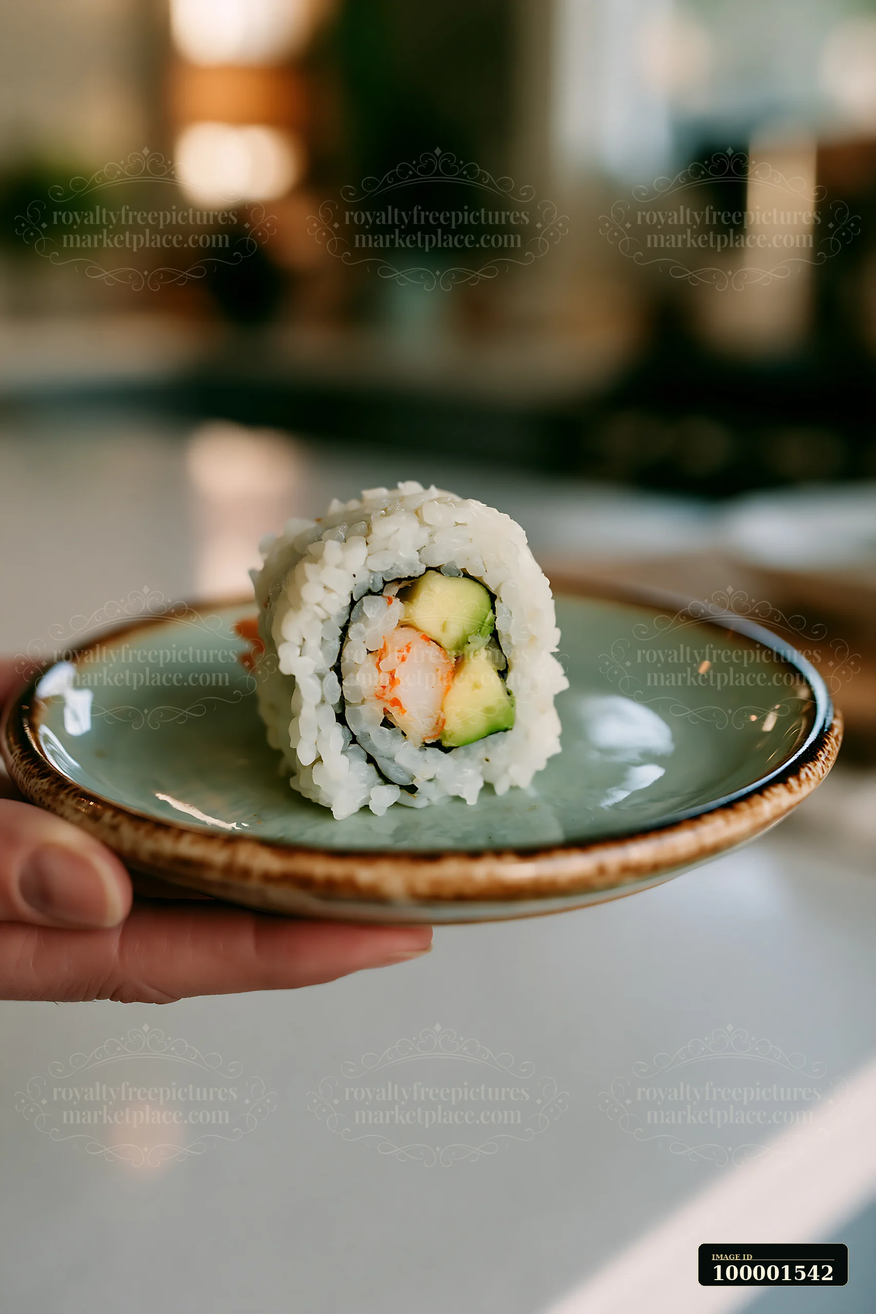A hand holds a plate with one California roll piece on plate, showcasing the sushi roll with shrimp and avocado in a bright kitchen setting.