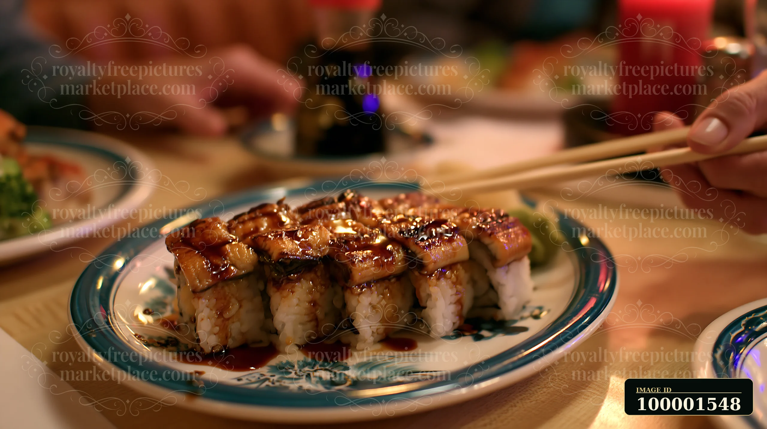 A close-up view of eel sushi with sweet sauce, served on a plate in a restaurant setting.