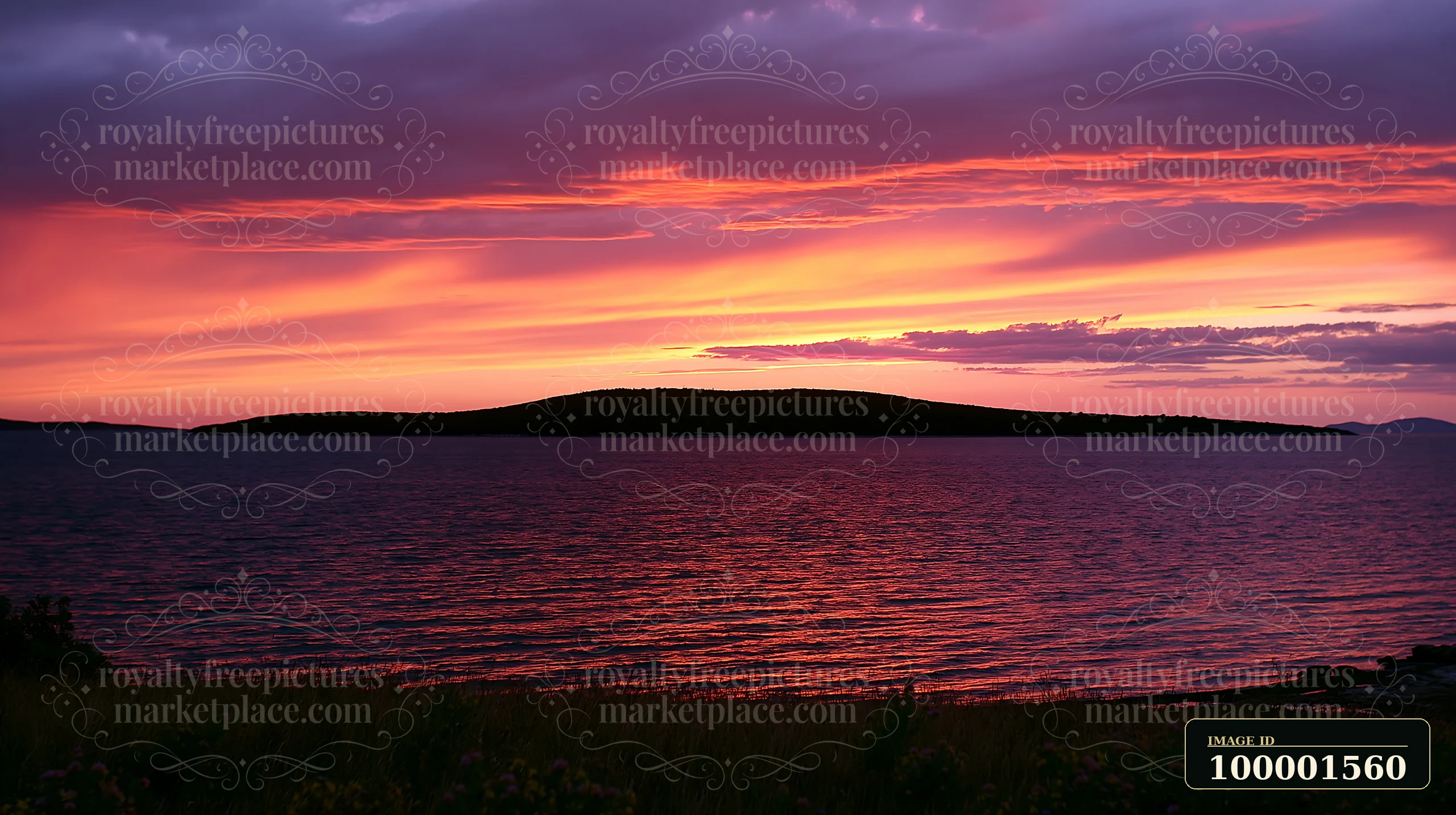 A vibrant sunset casts colorful hues over an island.