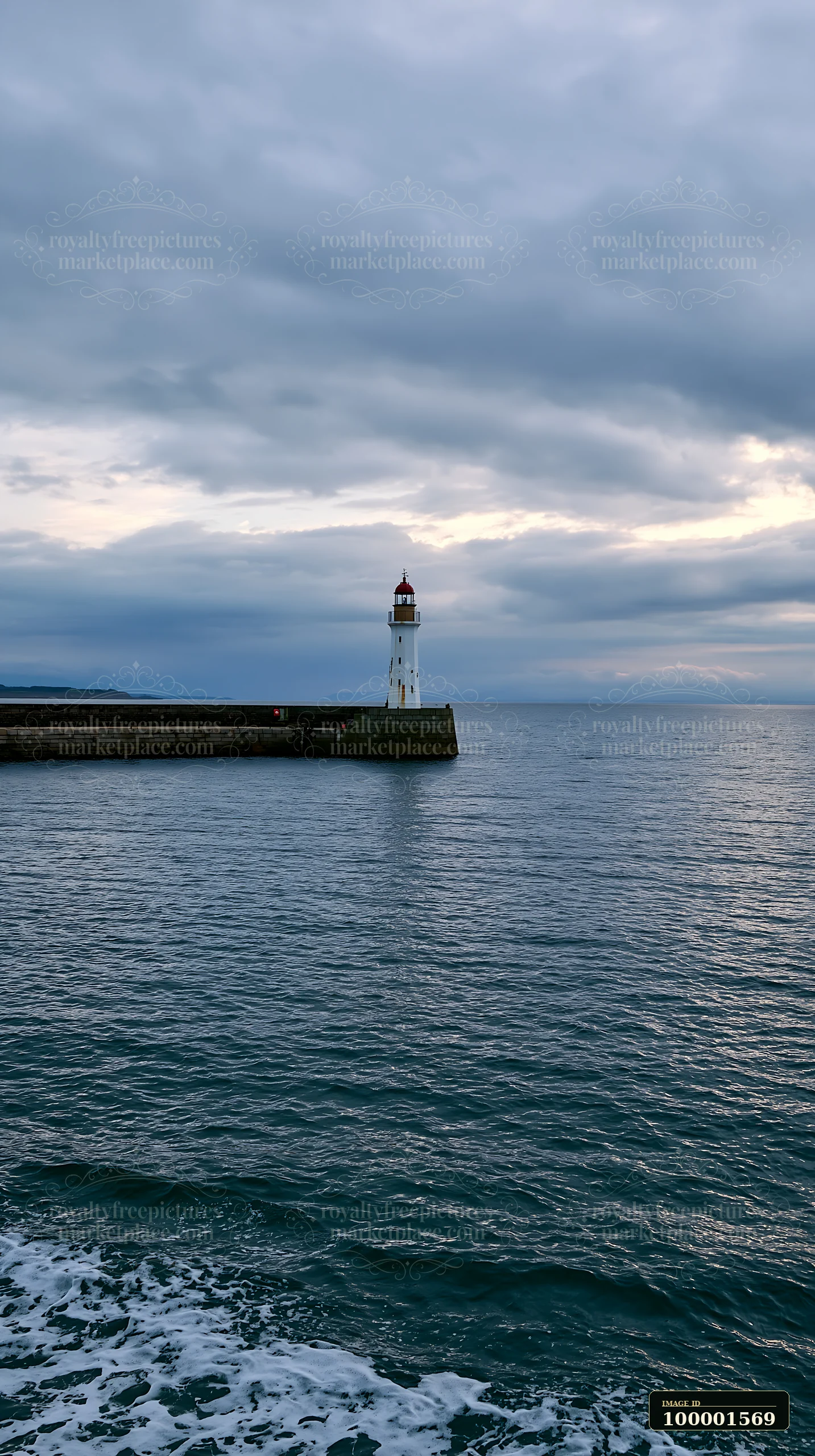 A lighthouse stands on a pier, surrounded by water as dusk approaches, under a cloudy sky.