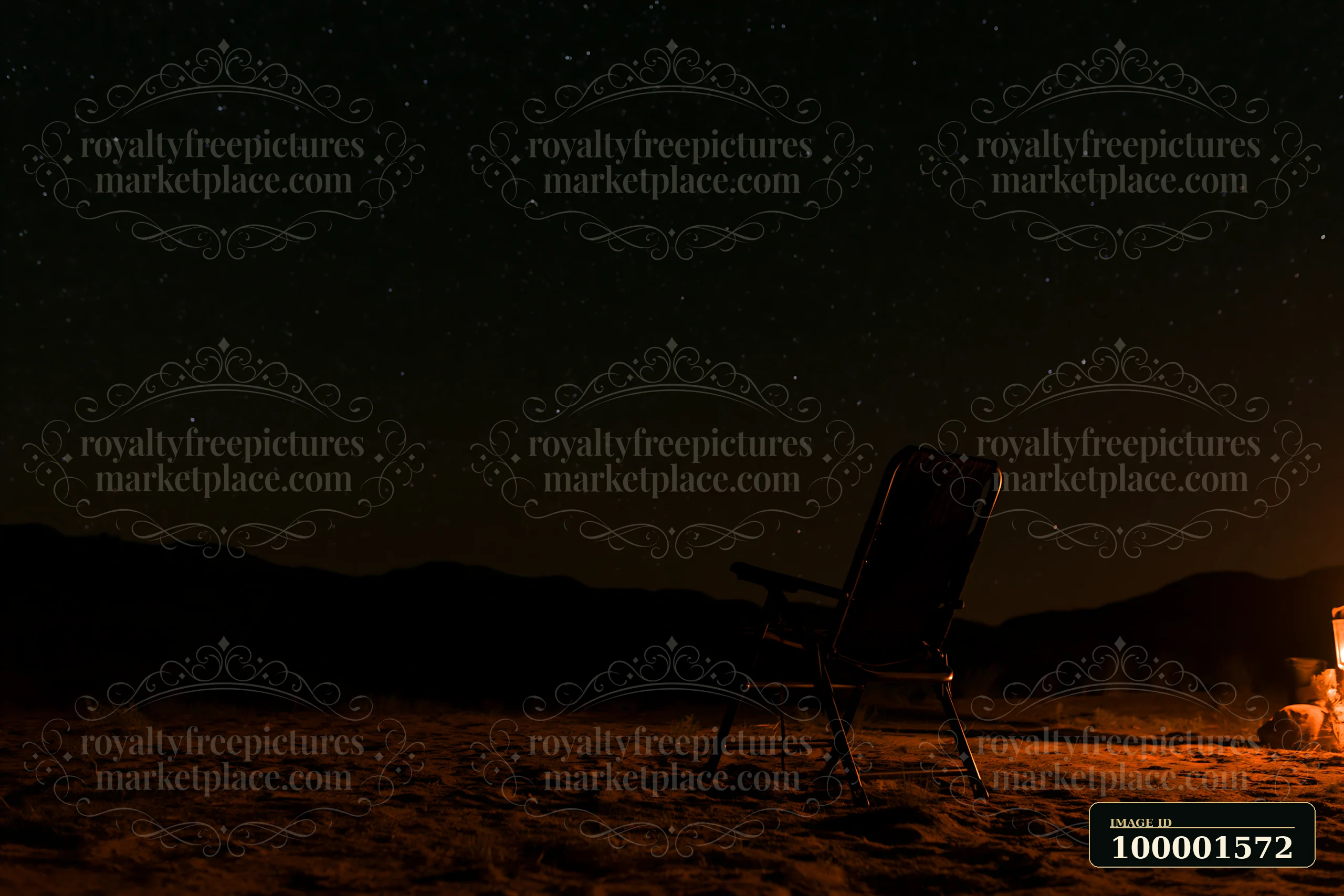 A chair sits near a fire pit in a desert campsite under a starry night sky.