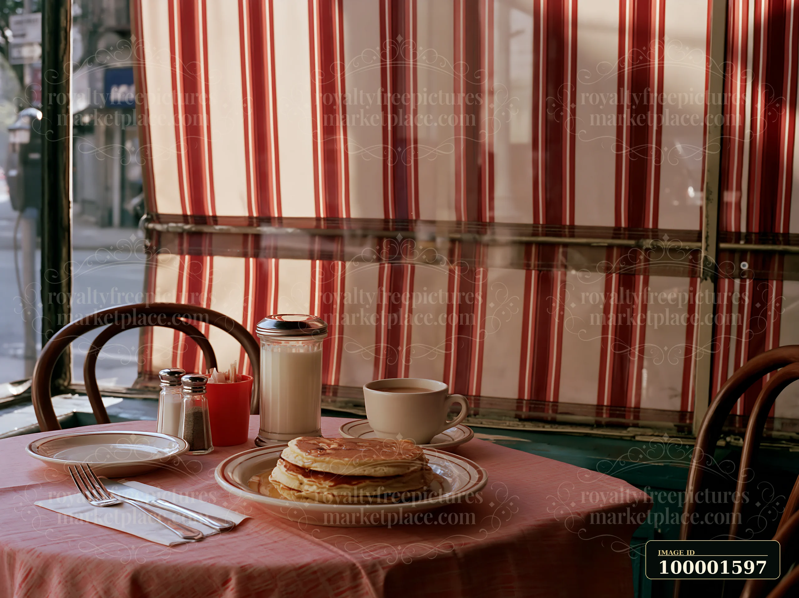 A table is set with pancakes, a glass of milk, and a cup of coffee in a cafe.