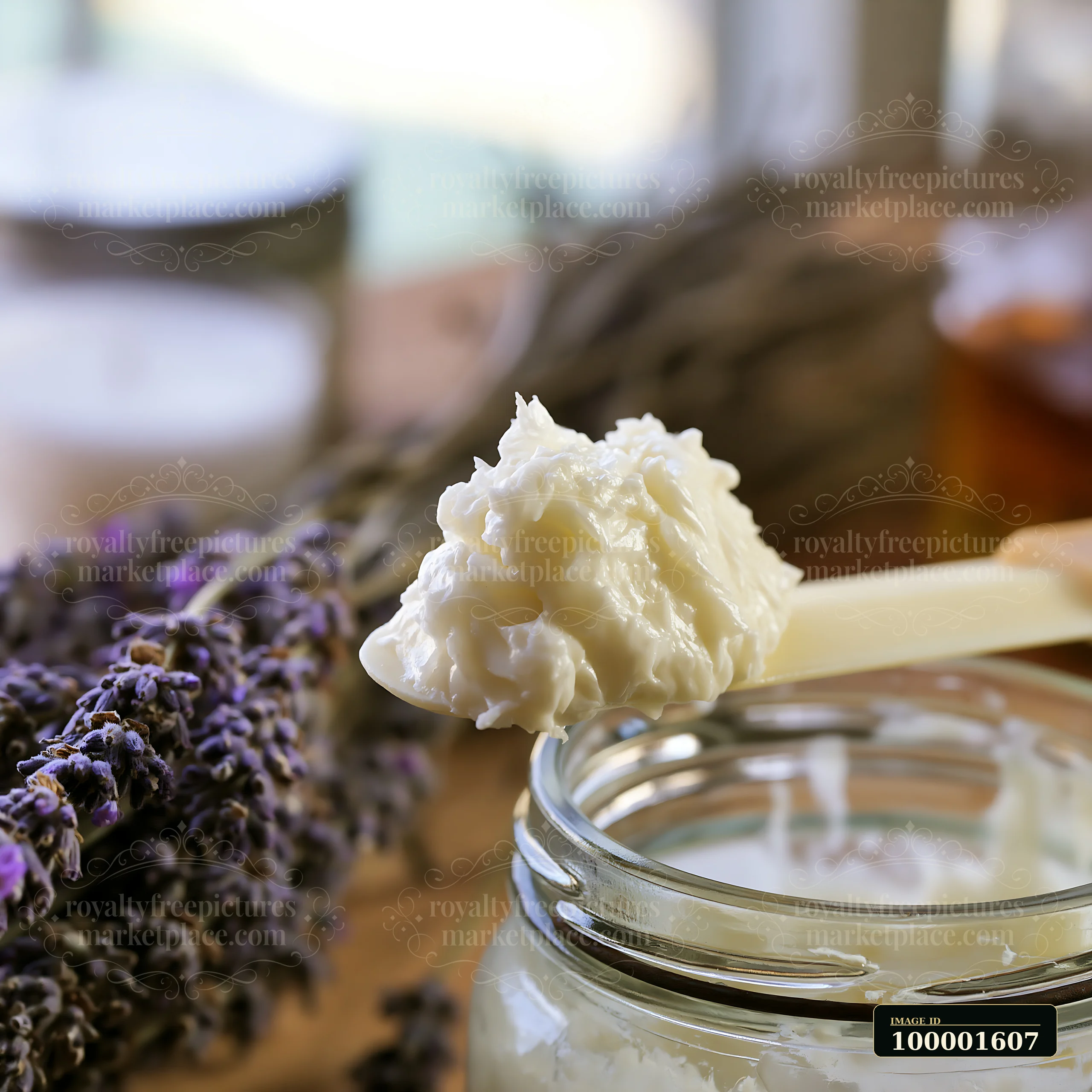A spatula holds a dollop of cream above a glass container.