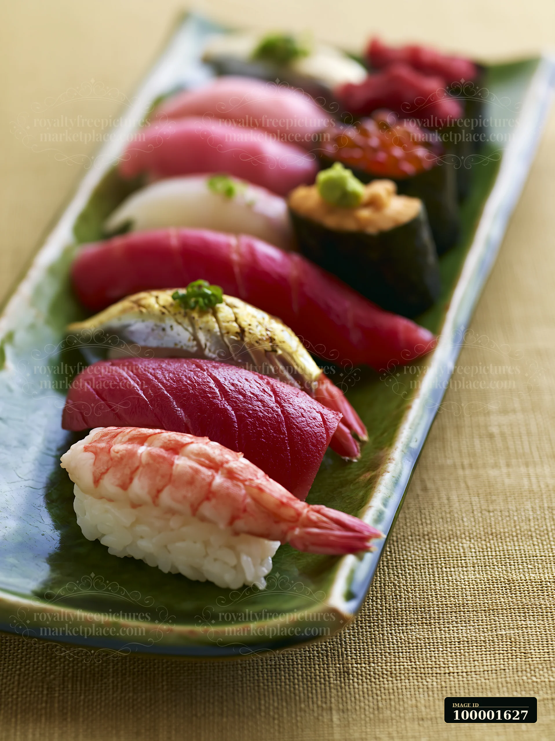 A sushi platter displays various types of sushi arranged neatly on a green plate, showcasing vibrant colors against a light background.