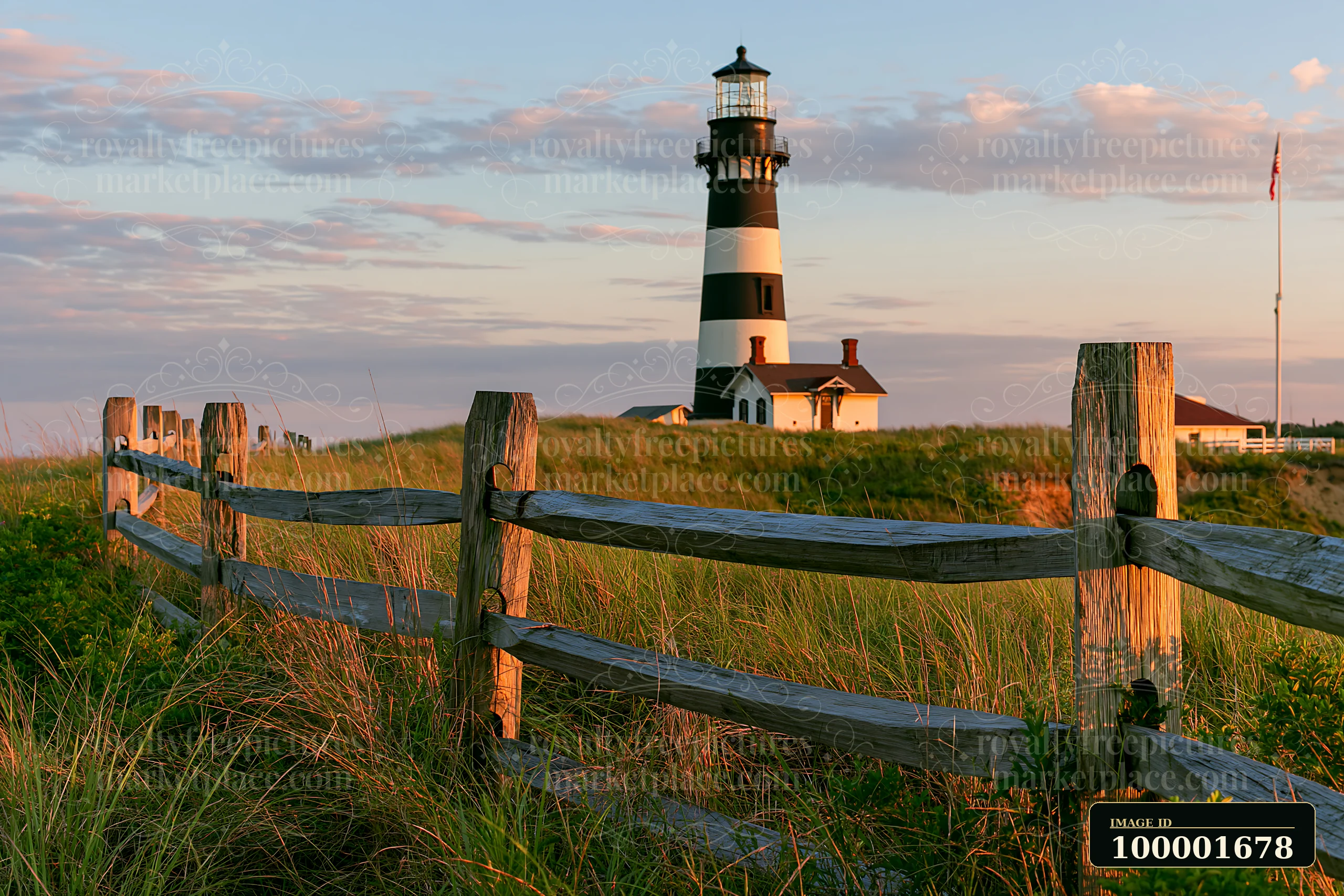 A lighthouse with black and white stripes stands tall beside a wooden fence.
