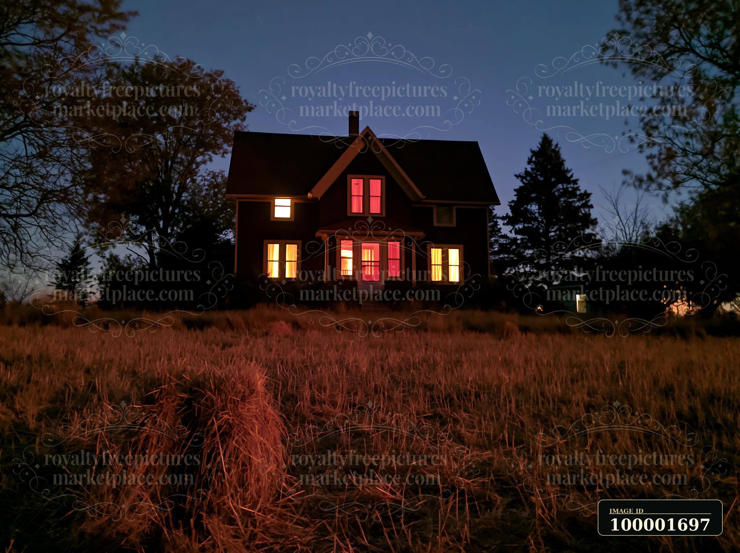A country home stands surrounded by fields at night with lights shining from its windows.