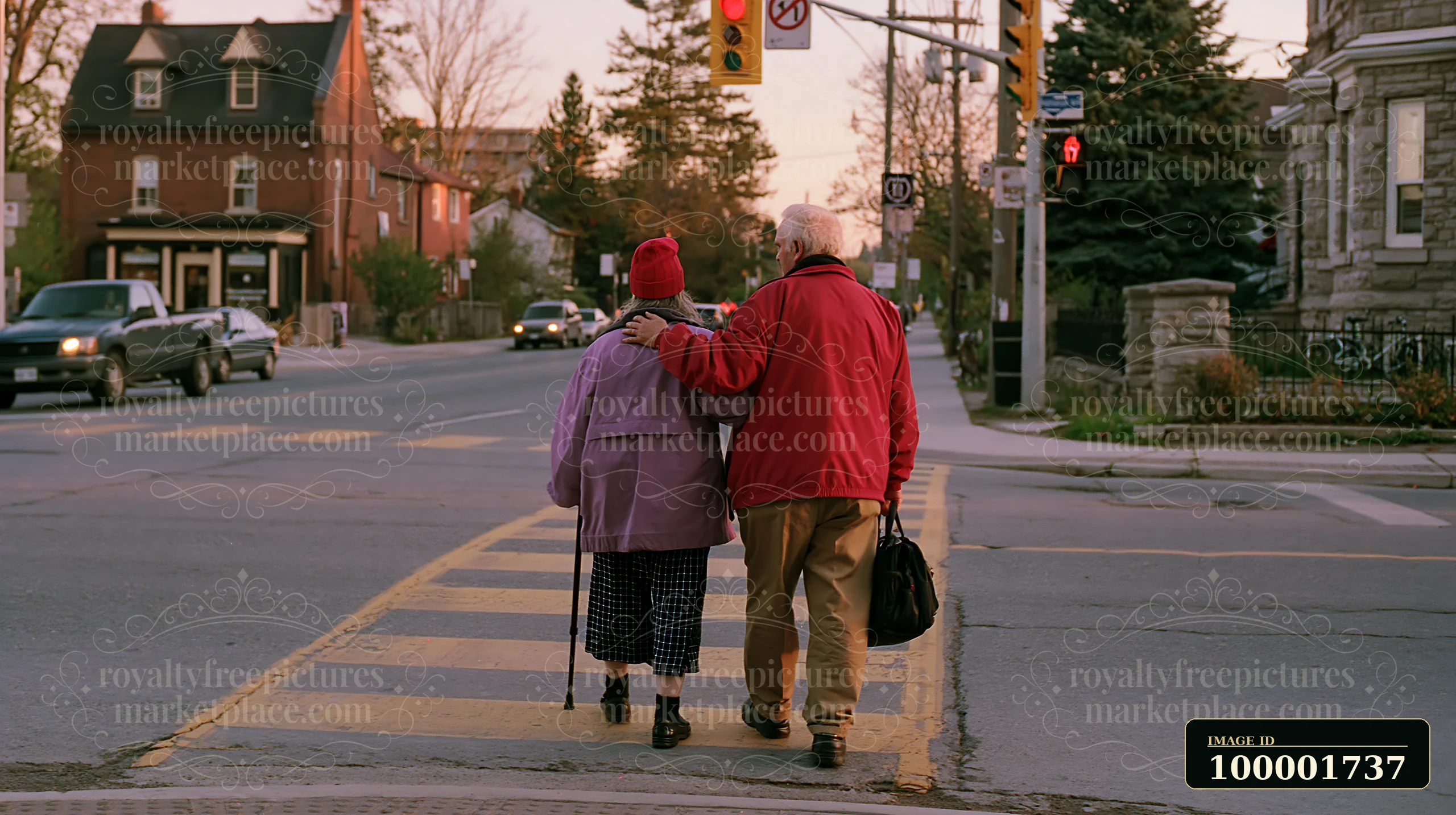 A person with Parkinson's disease receiving support walks with a companion on a city street near traffic lights during sunset.