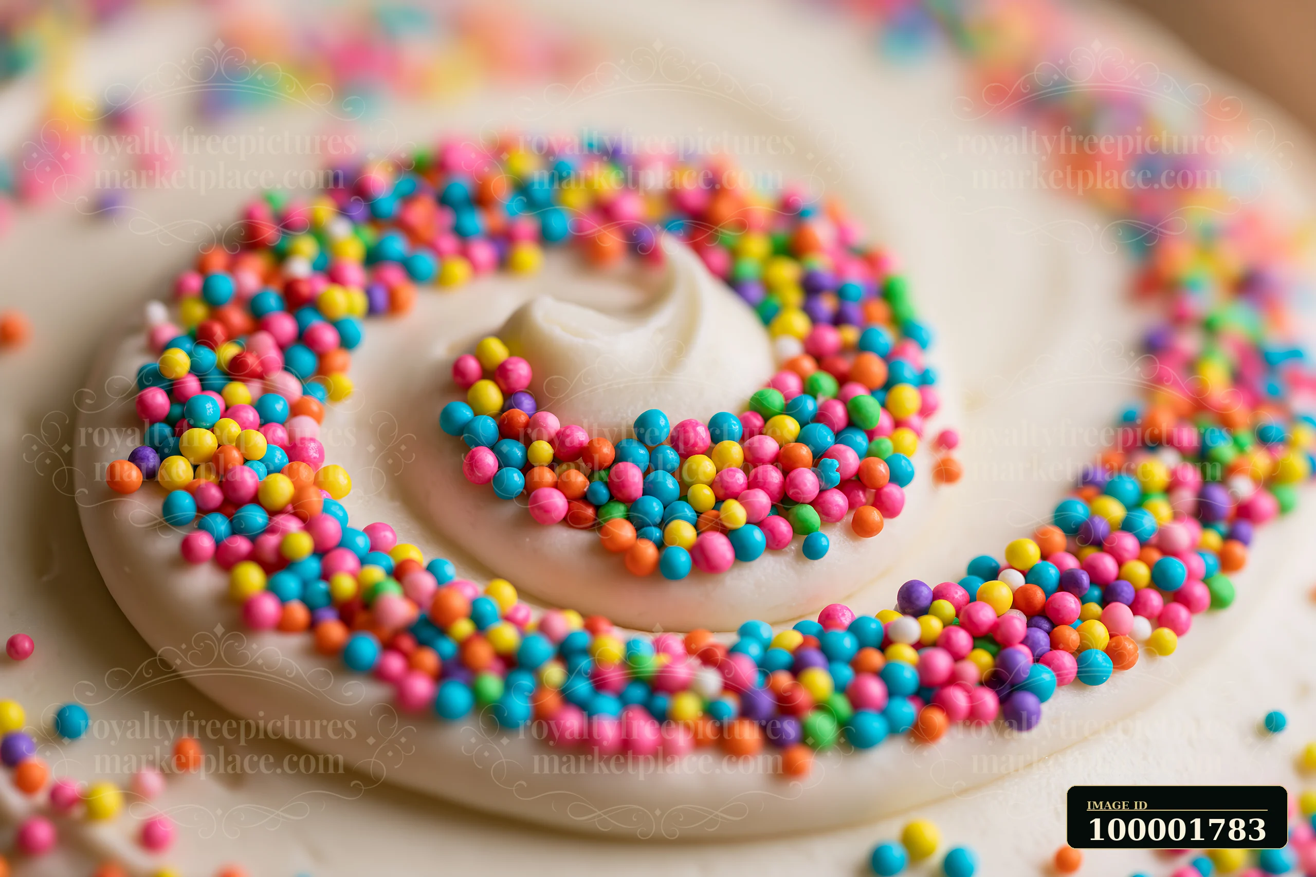 Rainbow sprinkles arranged in a swirl on smooth white frosting create a vibrant pattern.