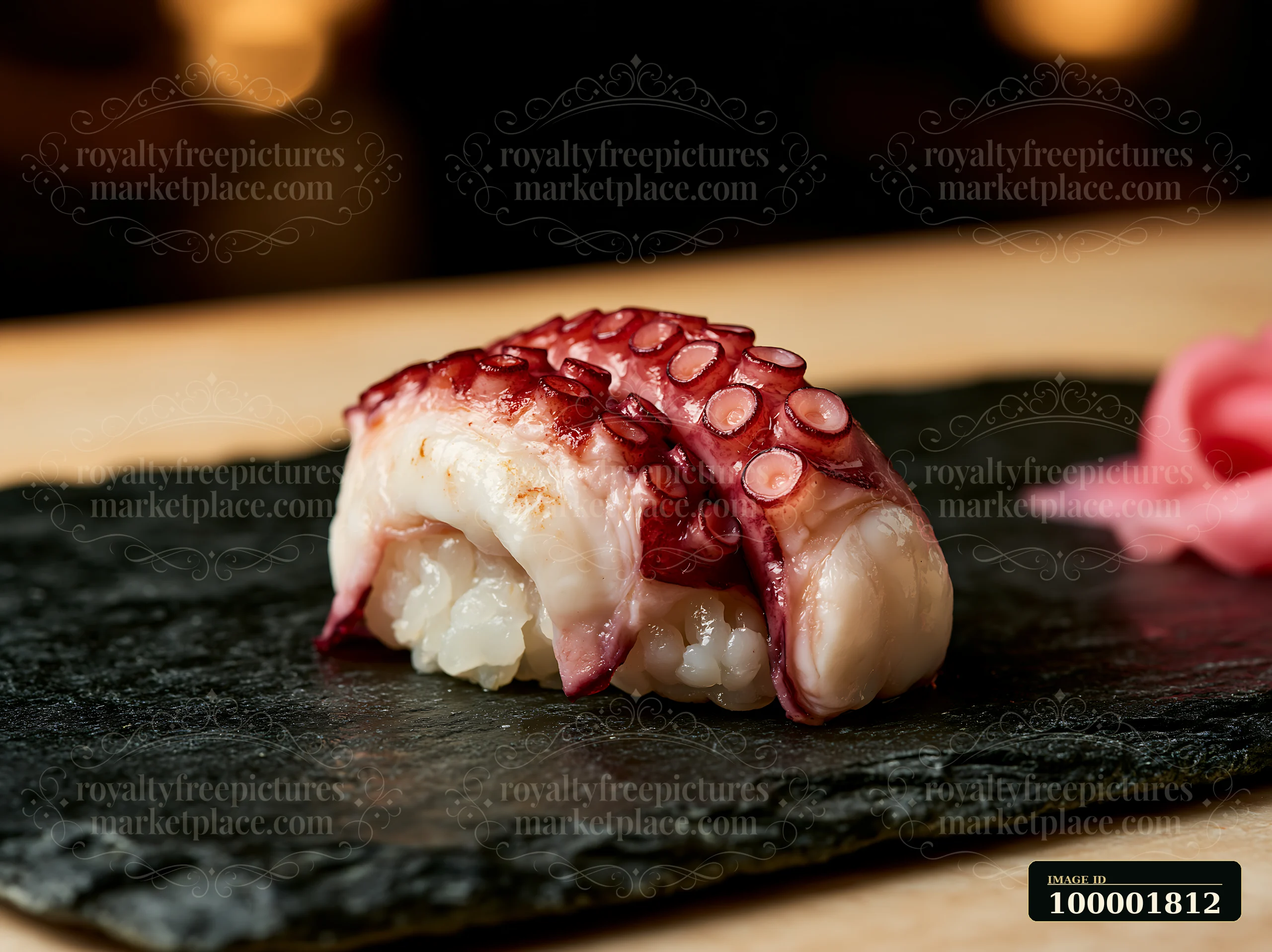 A single sushi piece on black slate features octopus atop vinegared rice, placed elegantly with a side of pickled ginger.