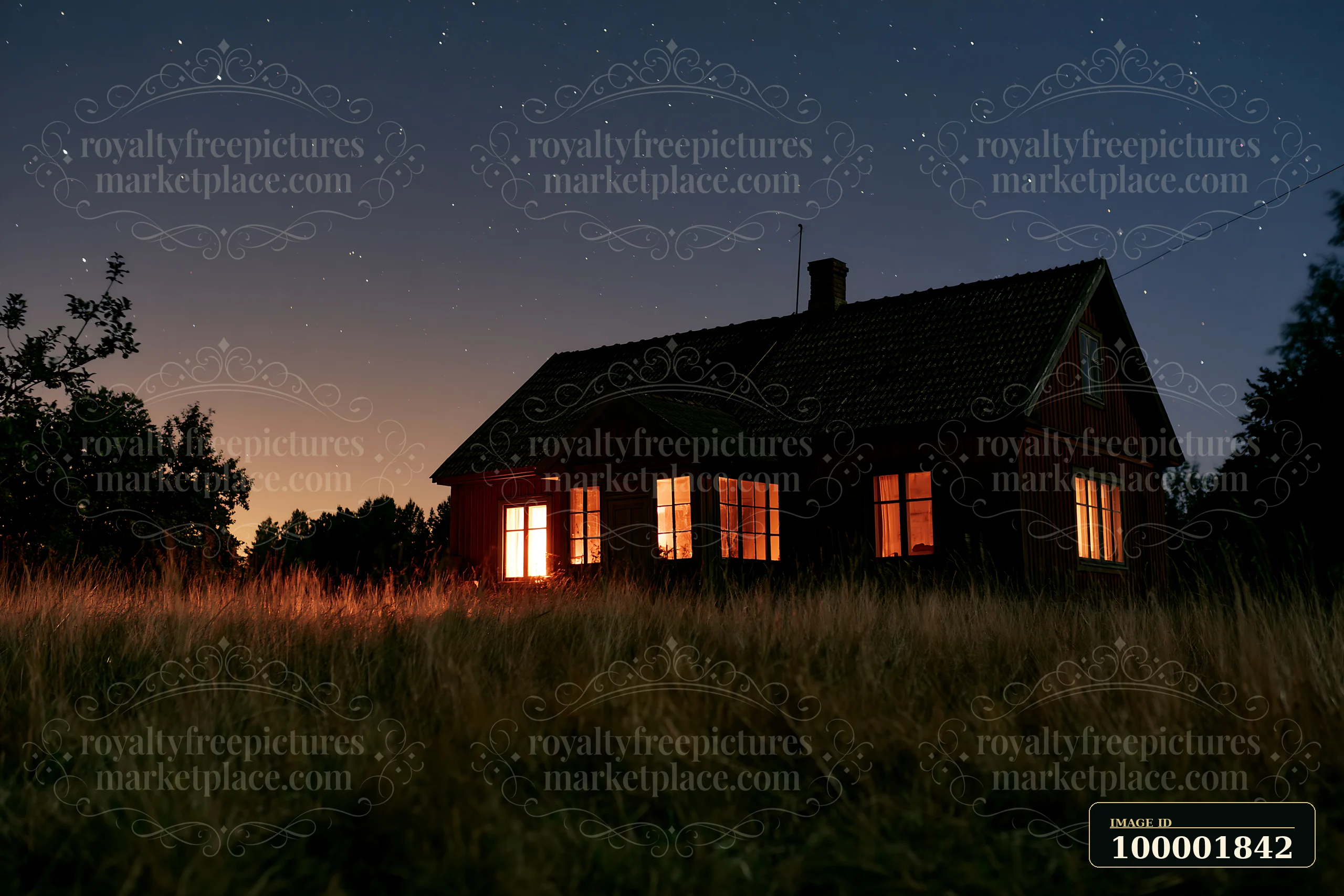 A country home stands in a field at night with bright windows shining.