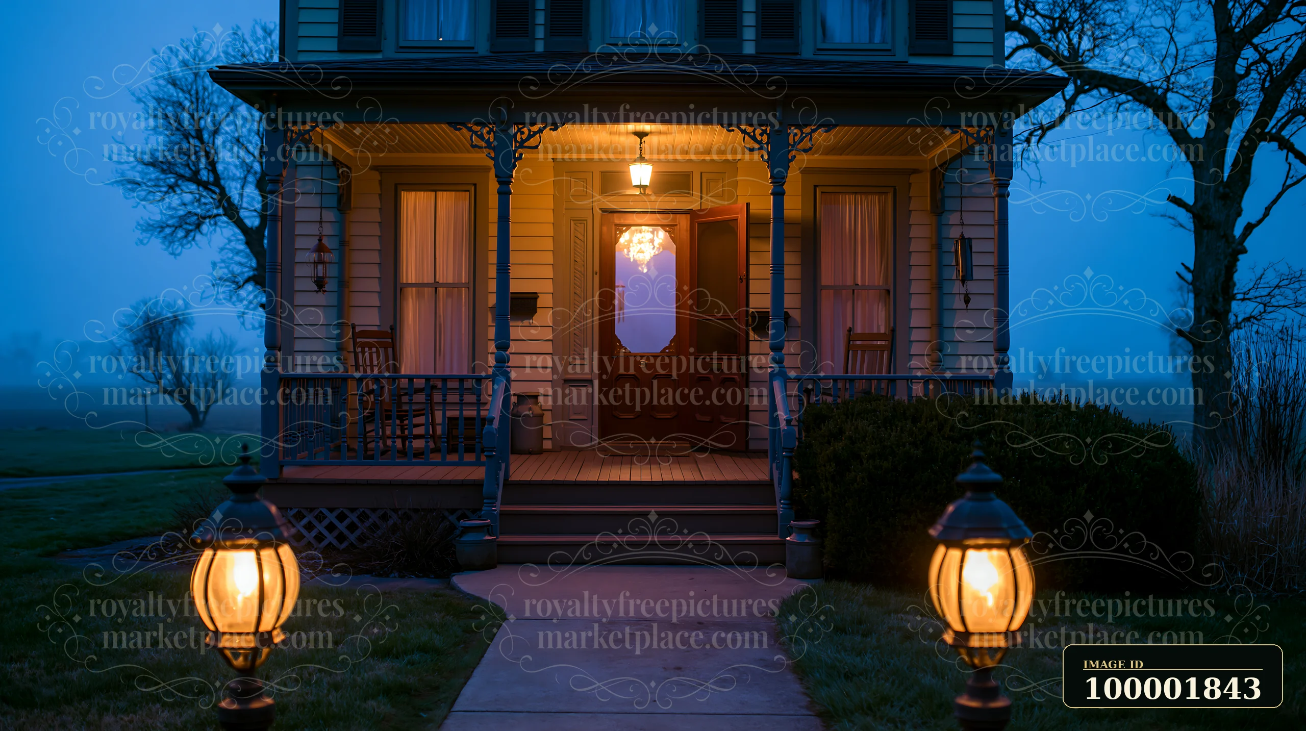 A country house with open front door is seen at dusk, illuminated by porch lights.